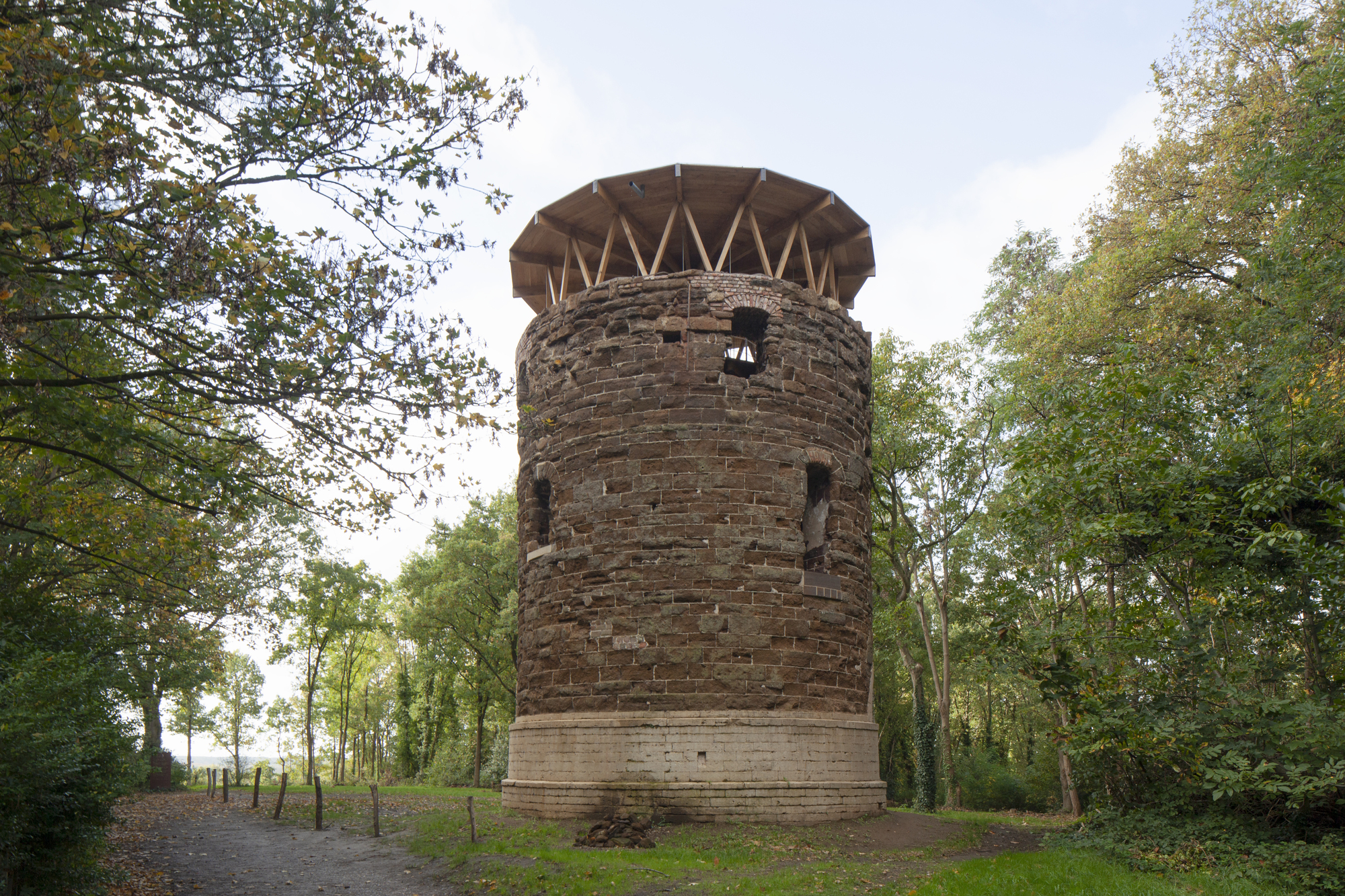 Front elevation of the restored brick tower with new timber crown in autumn woodland