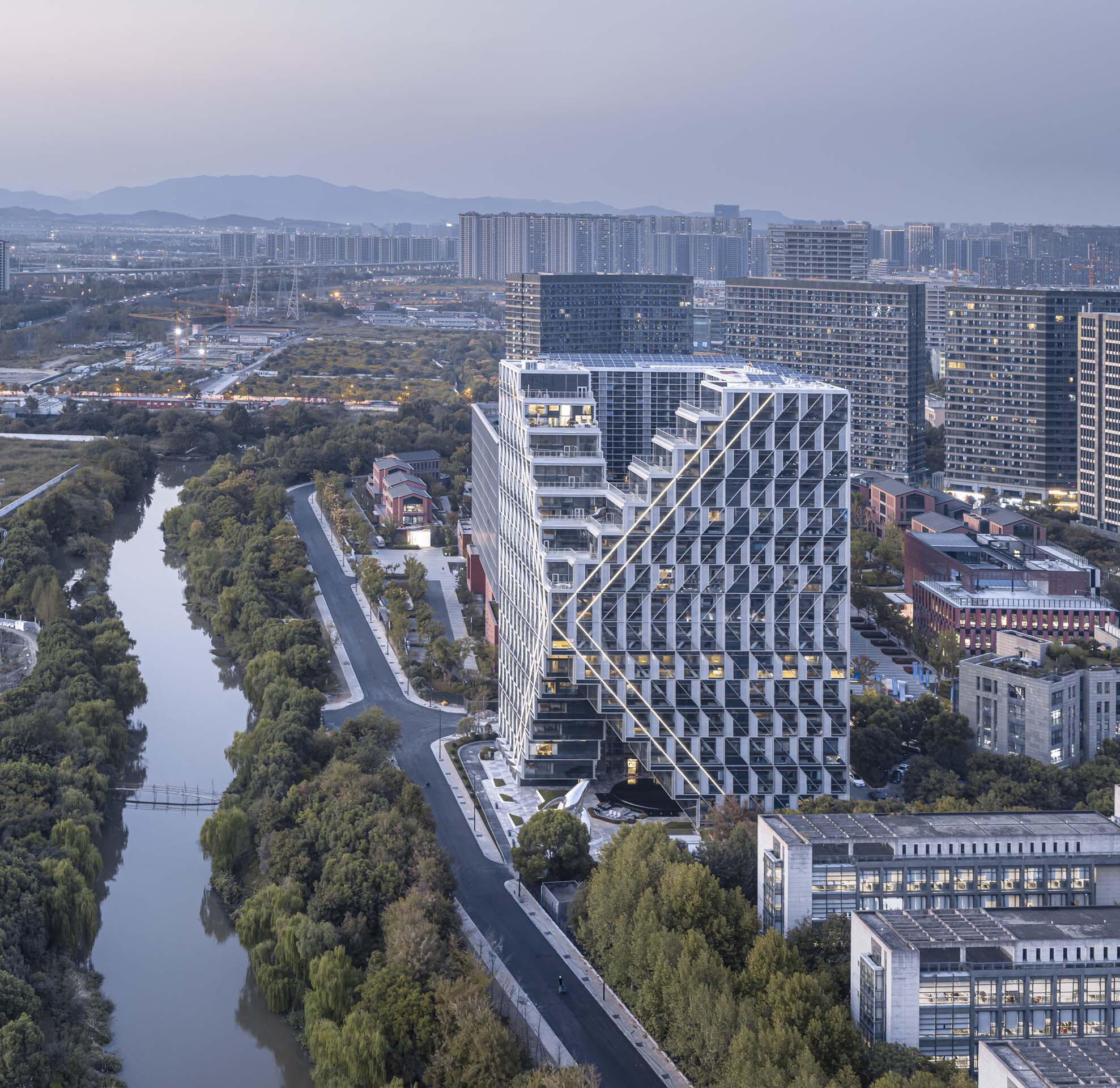 Elevated perspective showing the diagonal grid facade and stepped terraces beside the waterway