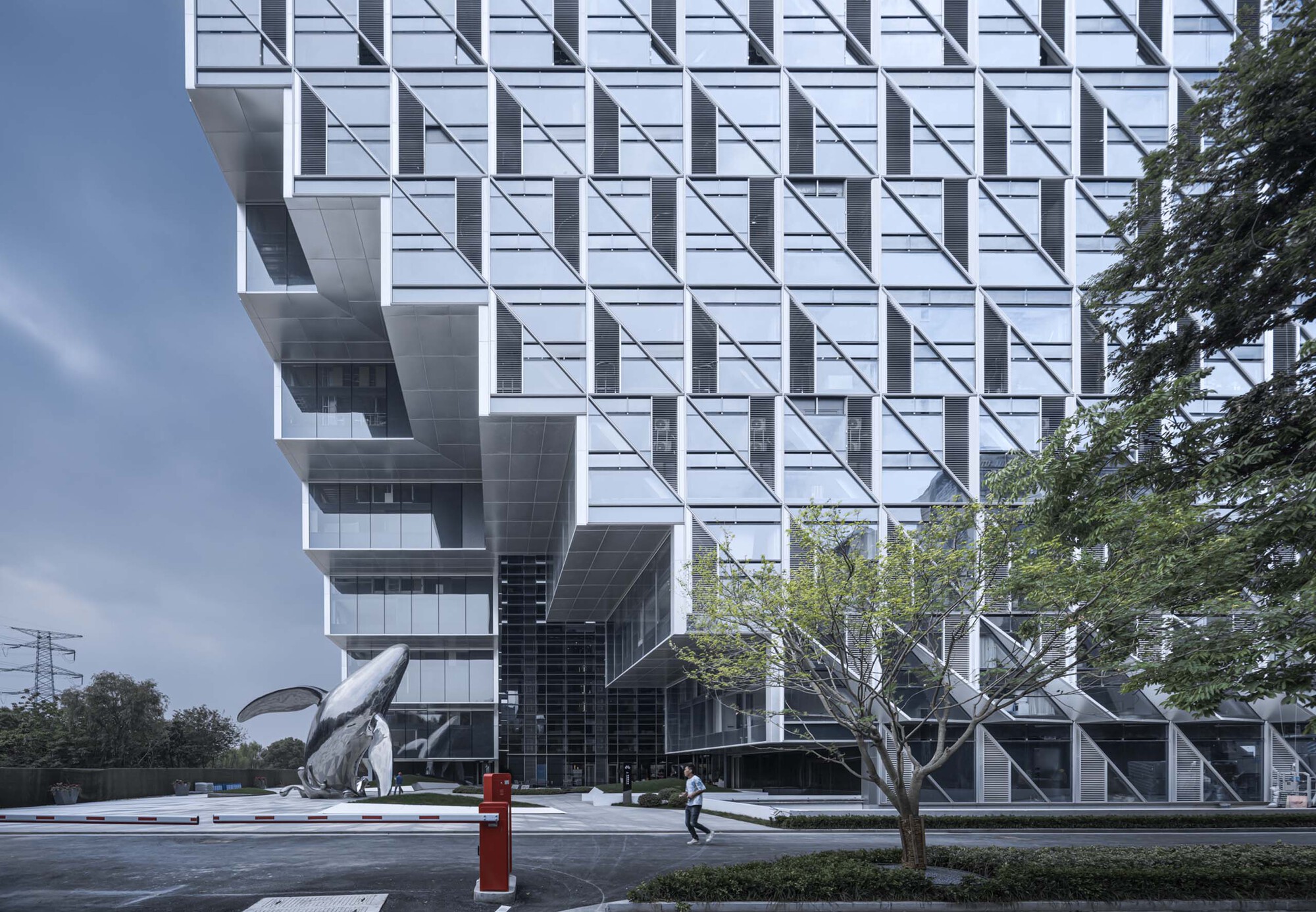 Street view of the white paneled facade with diagonal bracing patterns and a pedestrian crossing below
