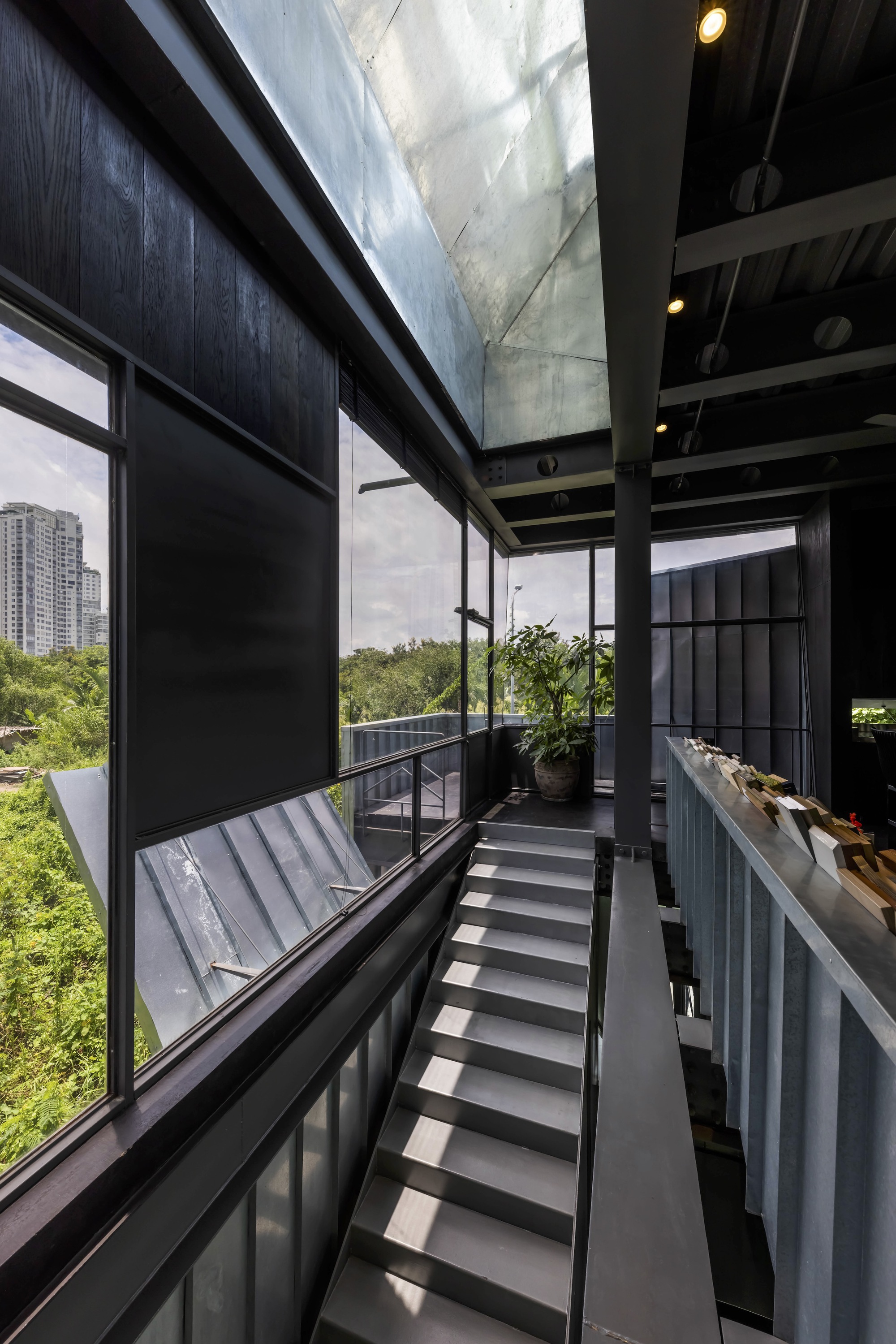 Interior staircase with metal treads and exposed steel beams beneath a concrete skylight shaft