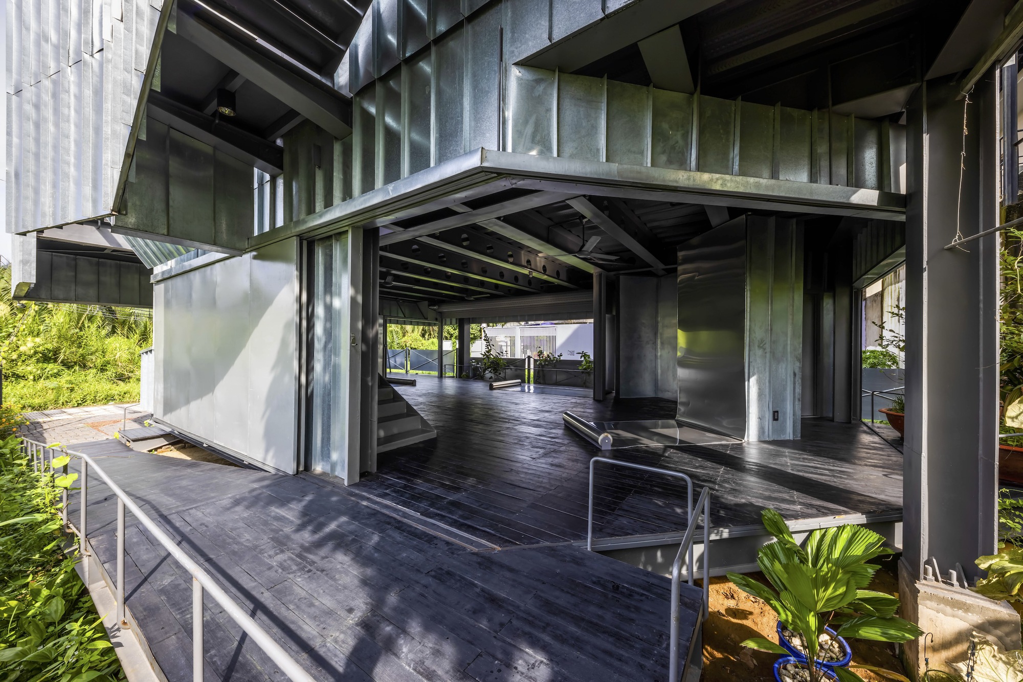 Covered terrace with operable metal panels, exposed concrete columns and timber decking