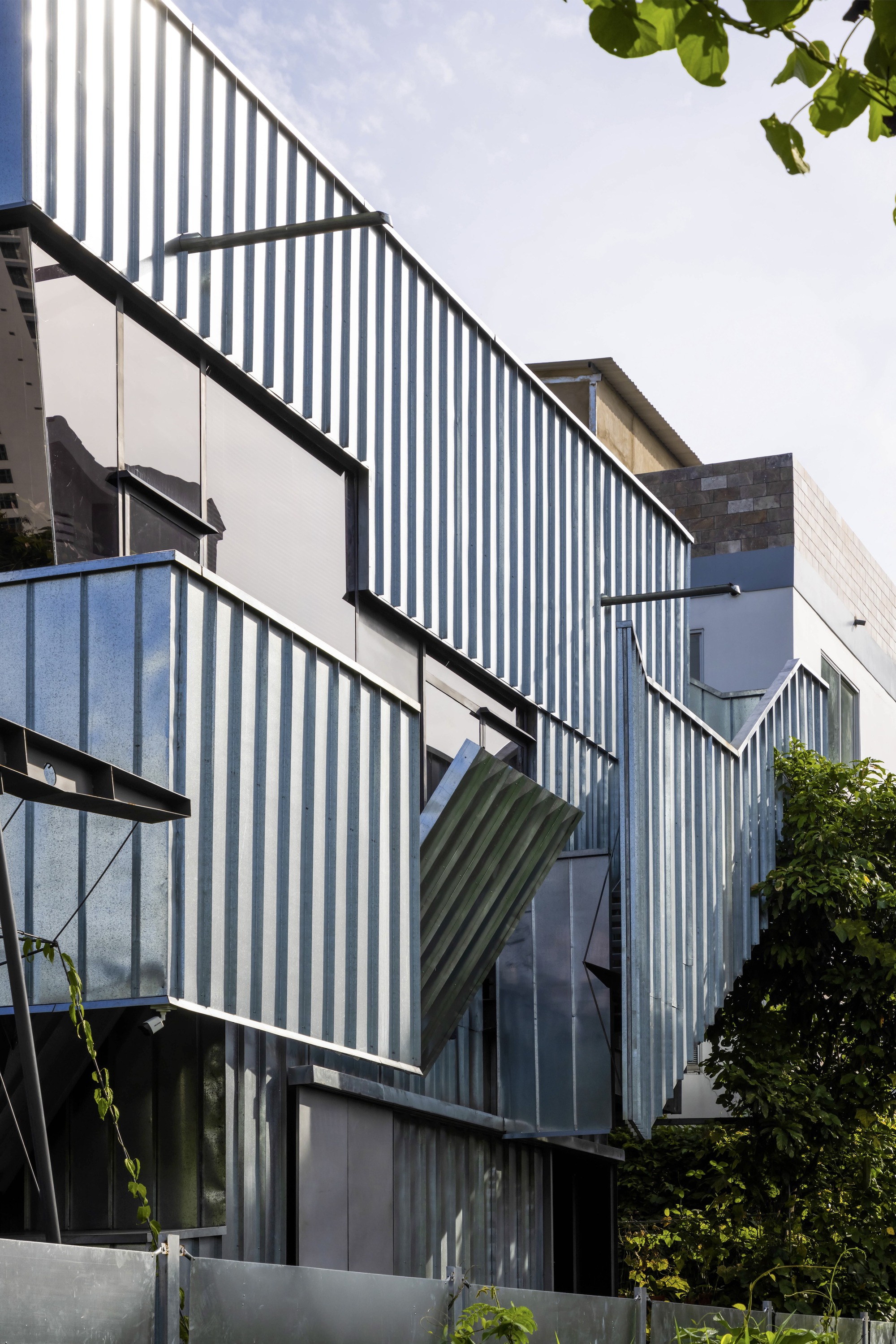 Detail of the articulated corrugated metal facade with angled panels and integrated window openings