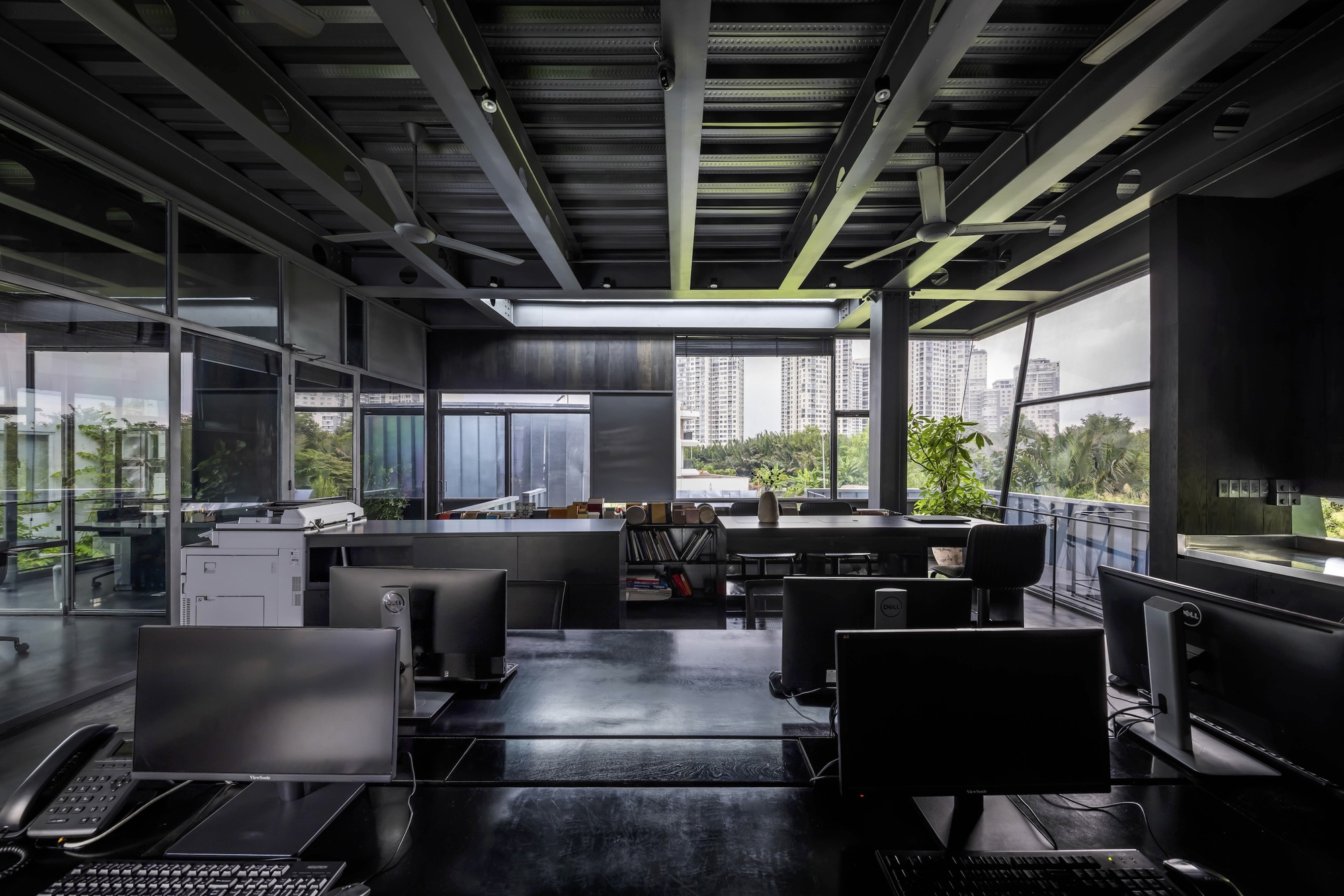 Office workspace with exposed steel ceiling structure and workstations arranged below continuous skylights