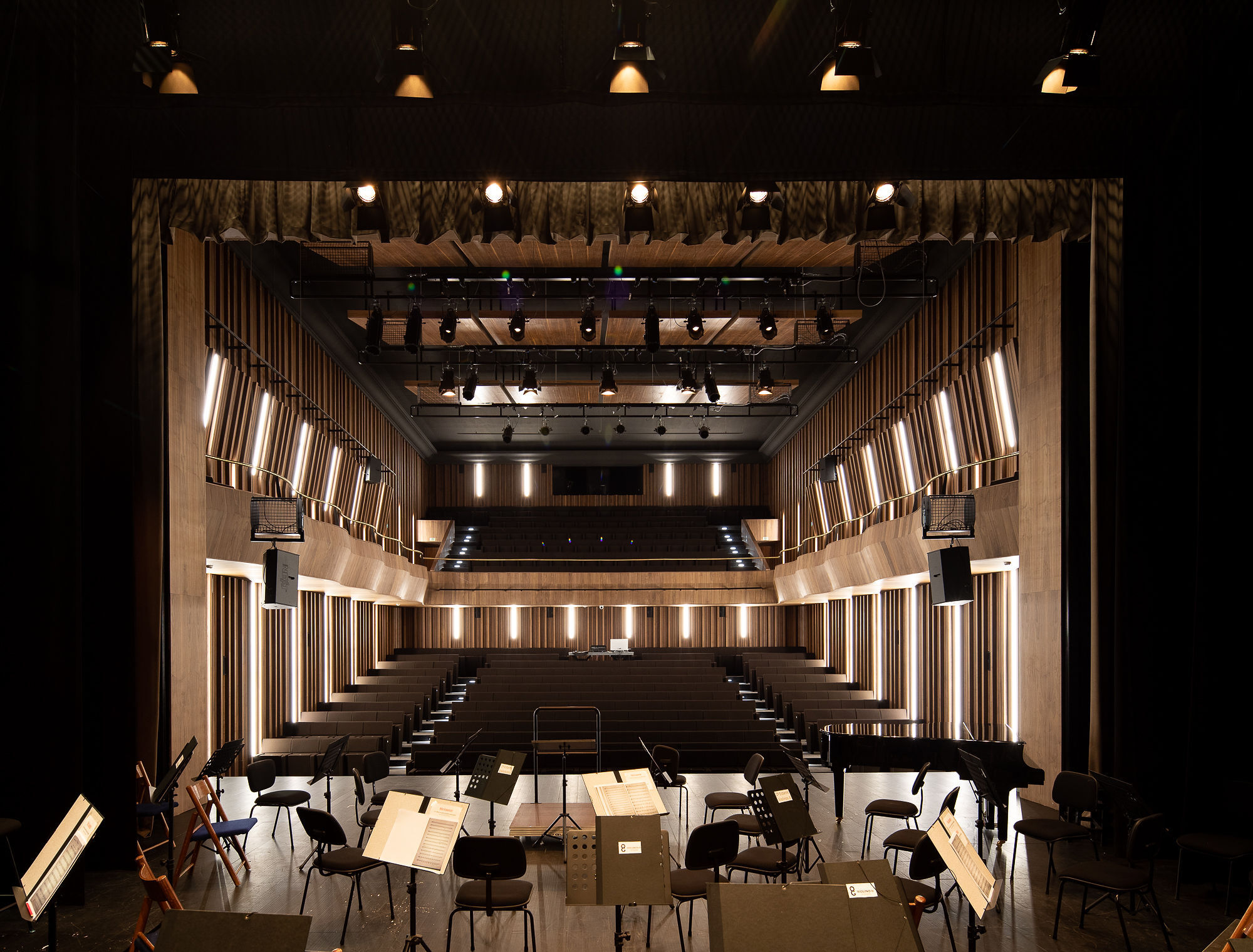 View from stage showing tiered timber seating, vertical illuminated panels and exposed ceiling rigging