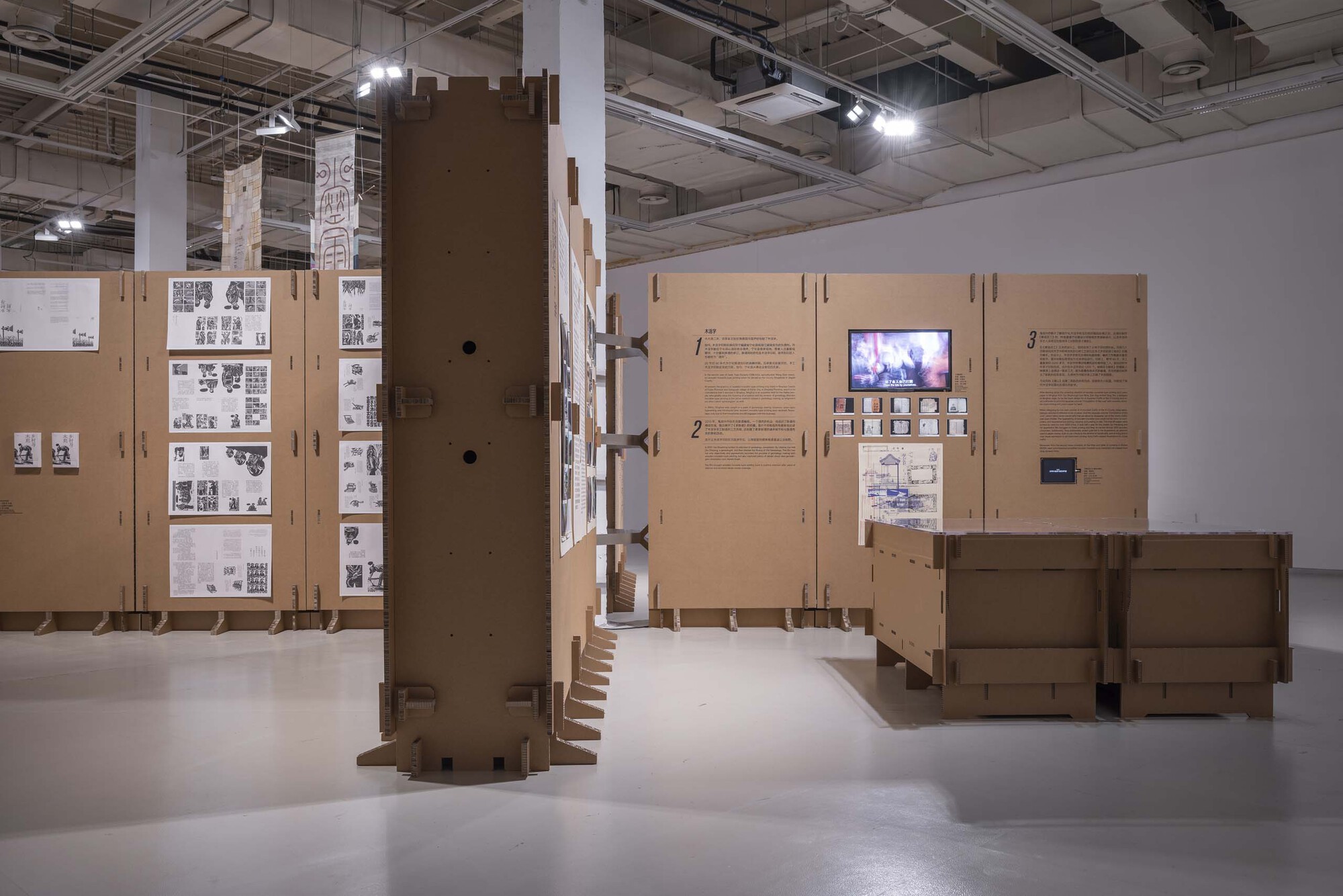 Cardboard wrapped structural column with slotted base and hinged display panels with embedded screen