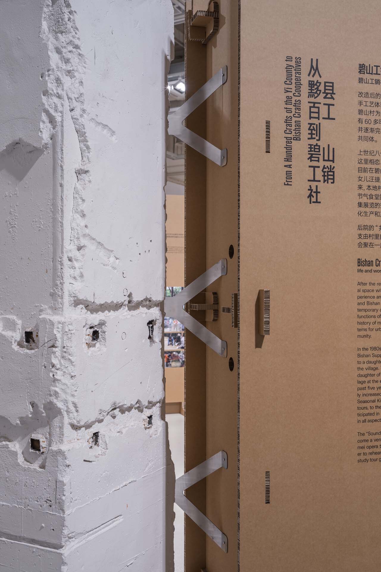 Detail of cardboard stairs and exhibition panels alongside a weathered white column
