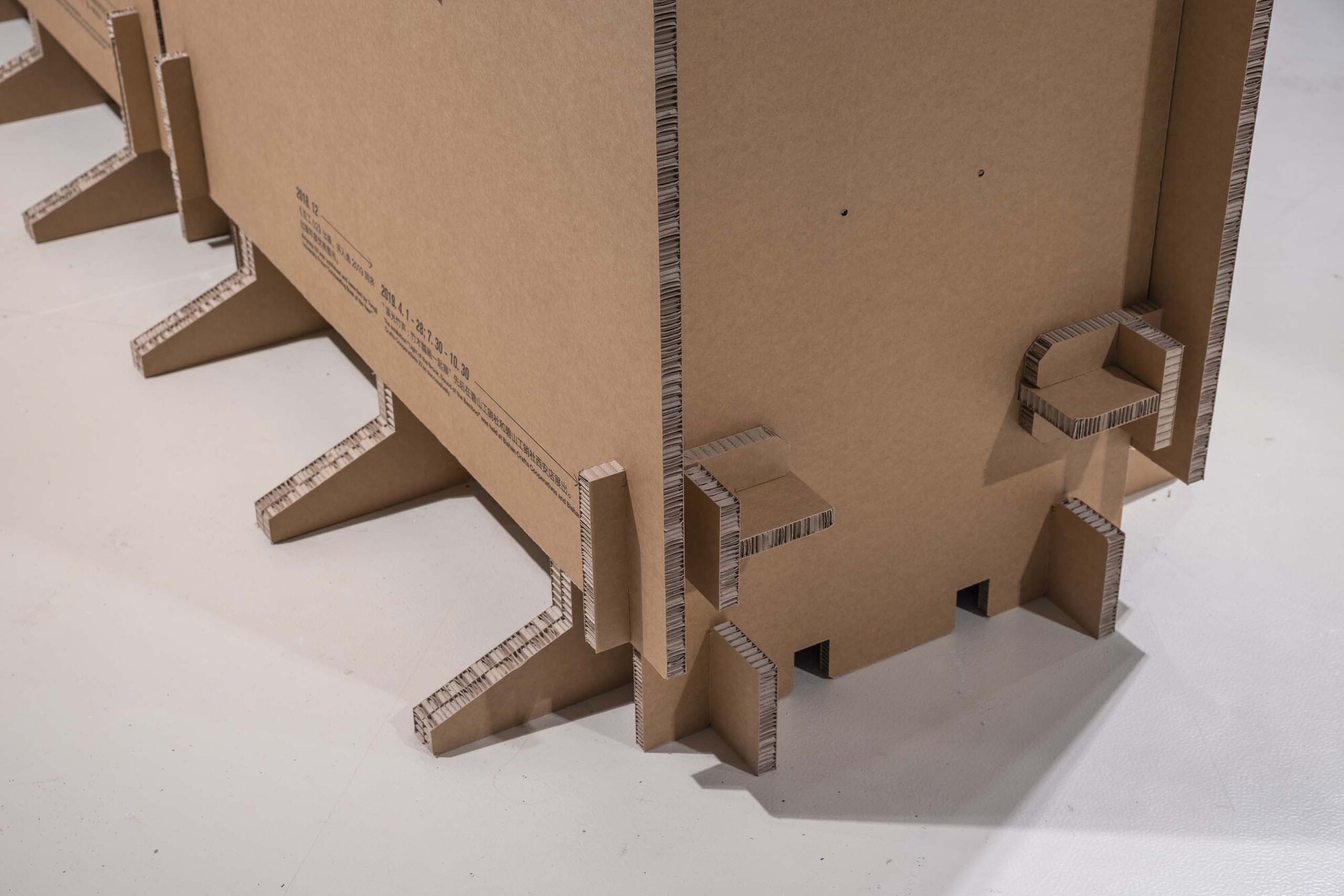 Close-up of corrugated cardboard structural supports and joinery at the model base