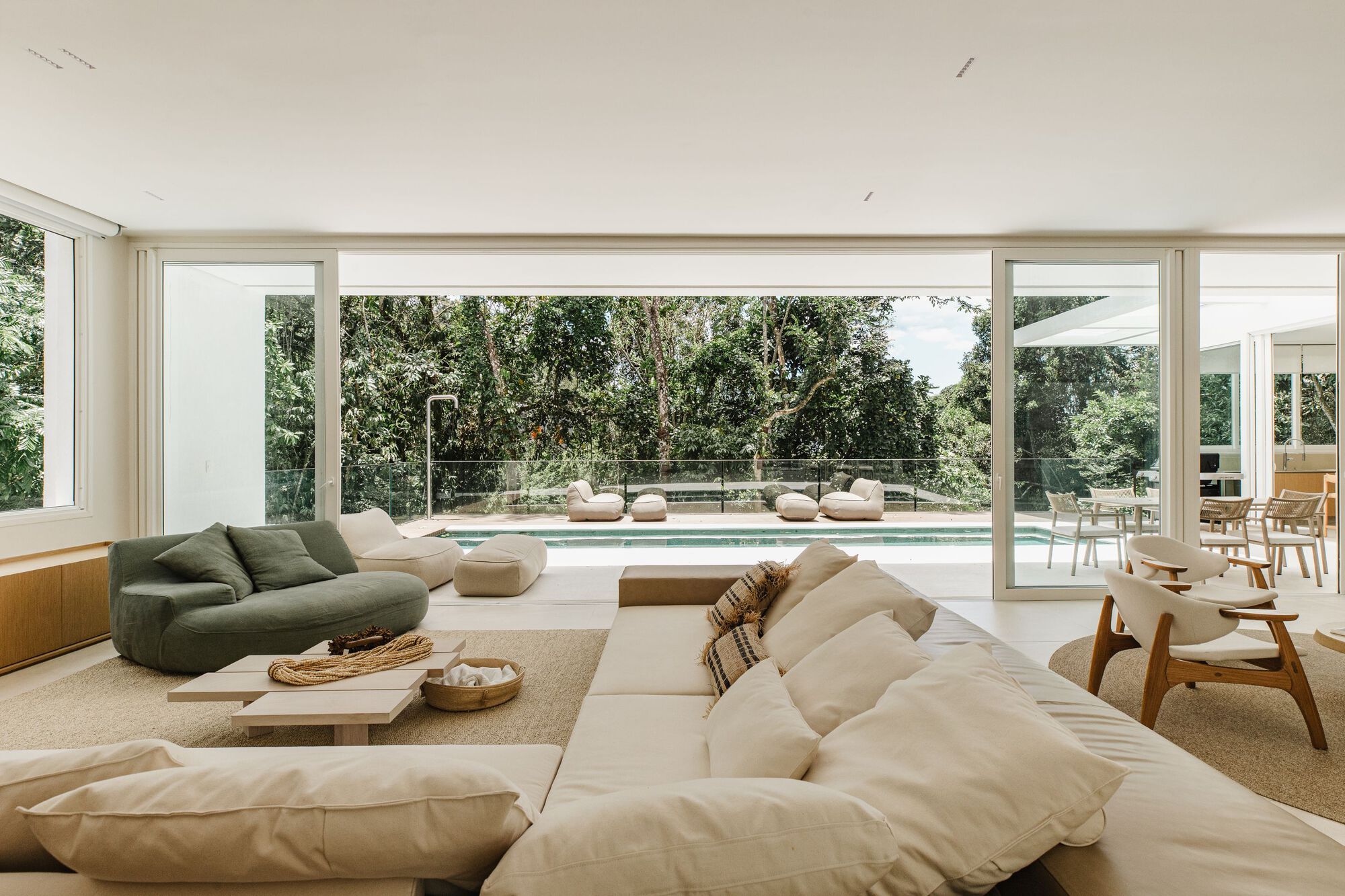 Living room with floor-to-ceiling glass walls overlooking a swimming pool and garden courtyard