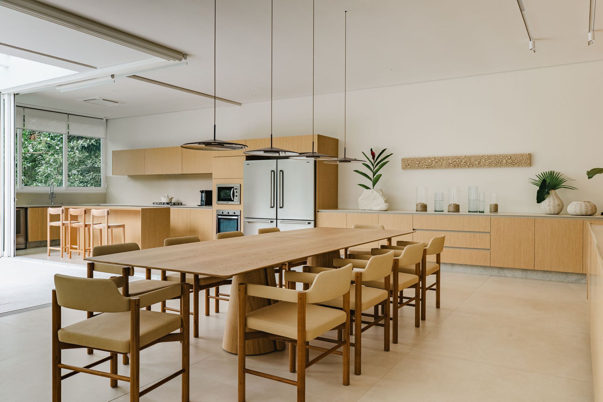 Open kitchen and dining area with timber cabinetry and suspended circular pendant light fixture