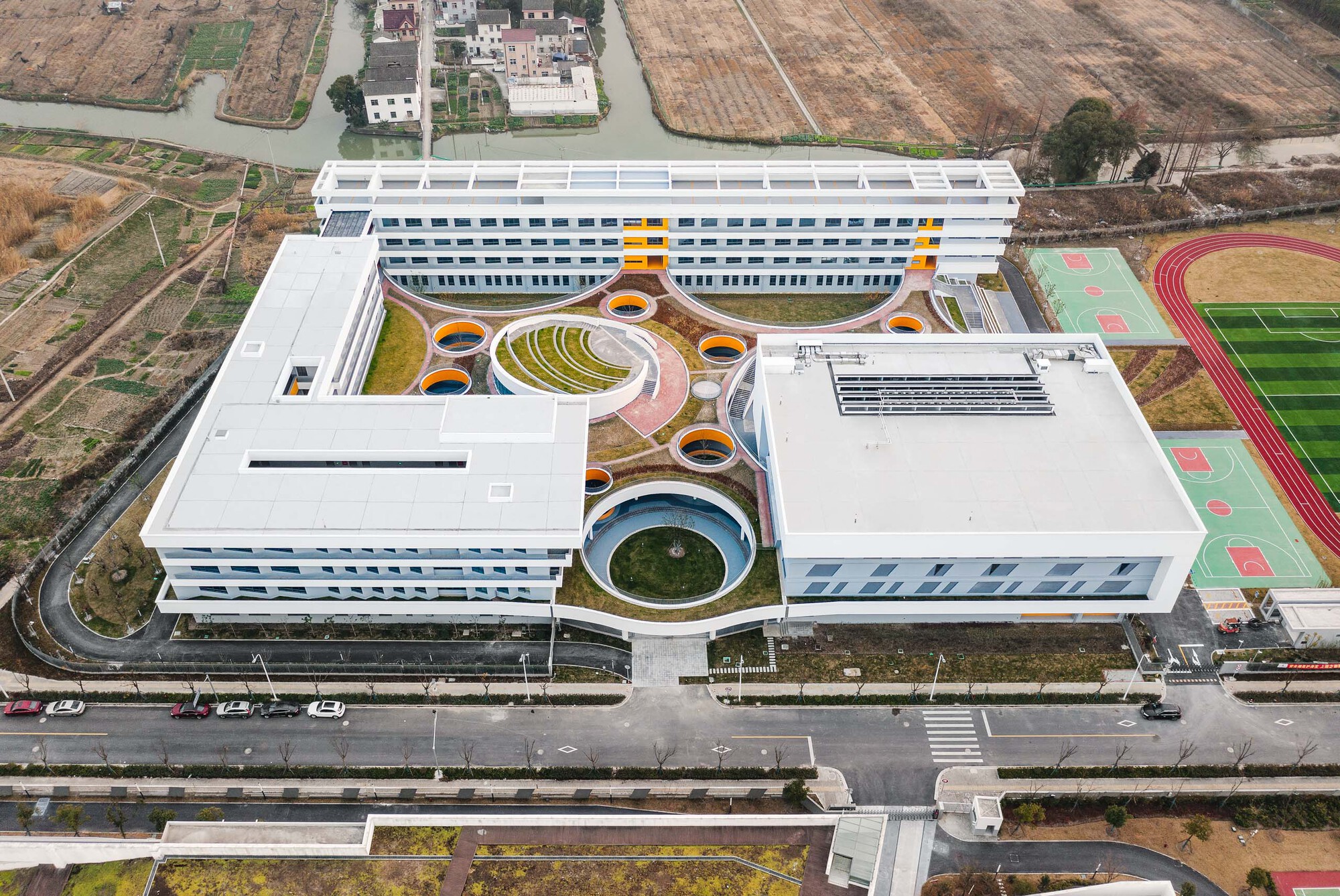 Drone view of the campus showing residential wings flanking the central courtyard with circular planters