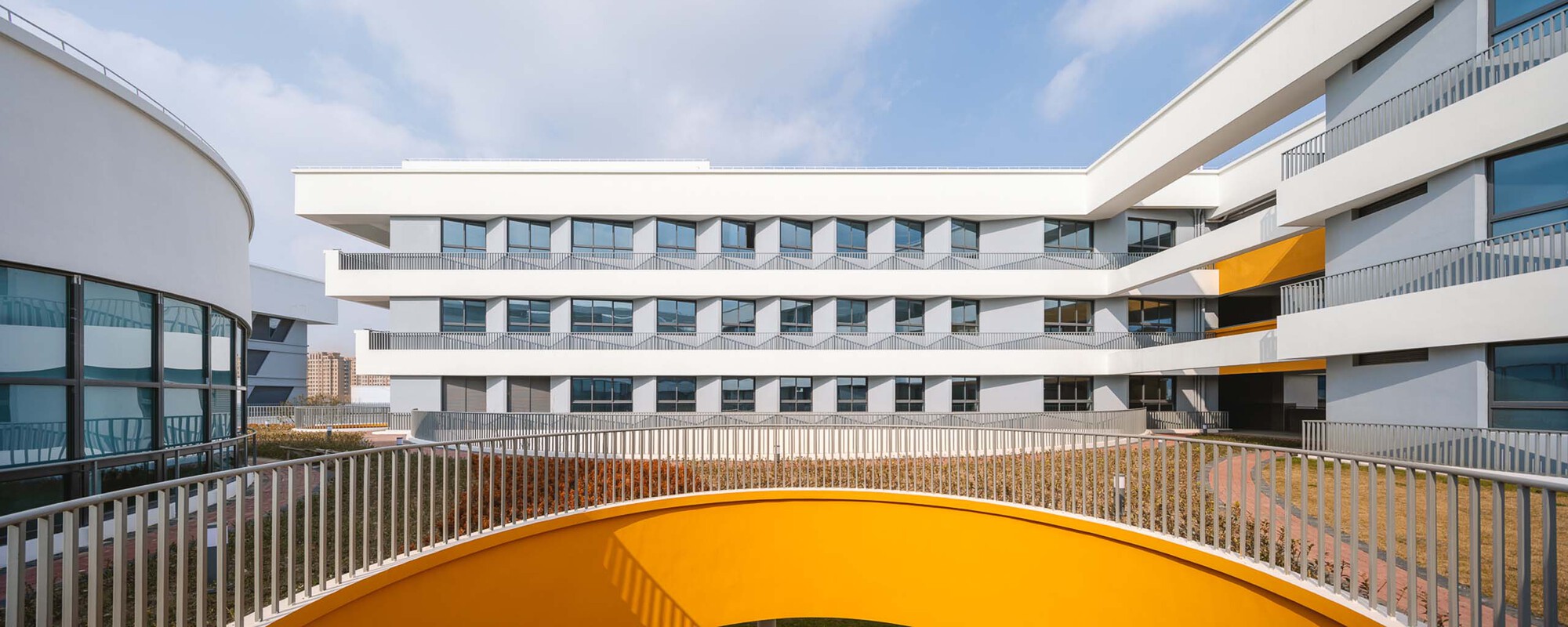 Rooftop courtyard with orange circular skylight surrounded by metal railings and planted beds