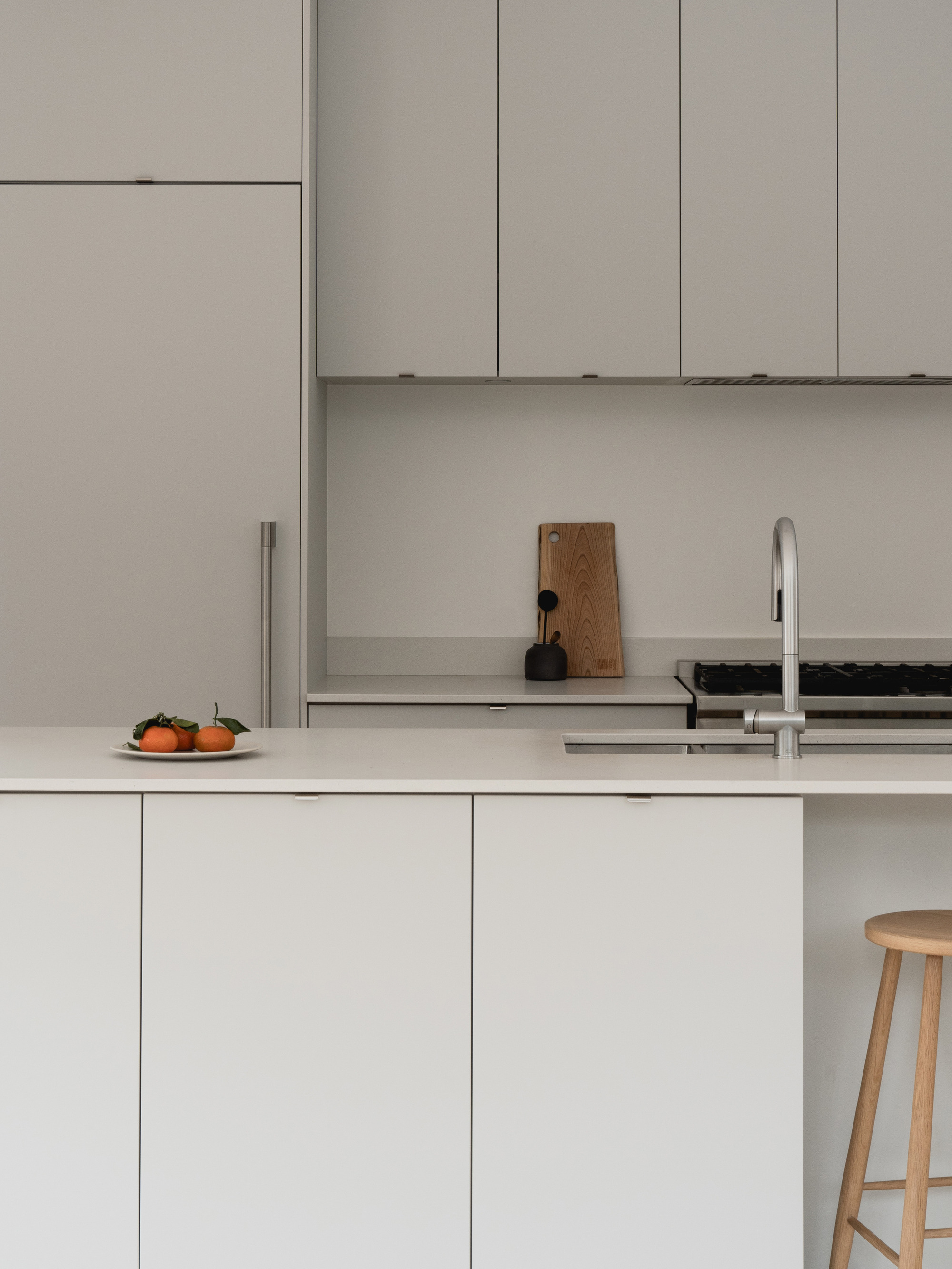 Kitchen counter with pale grey cabinetry, open shelving, and two persimmons beside the sink