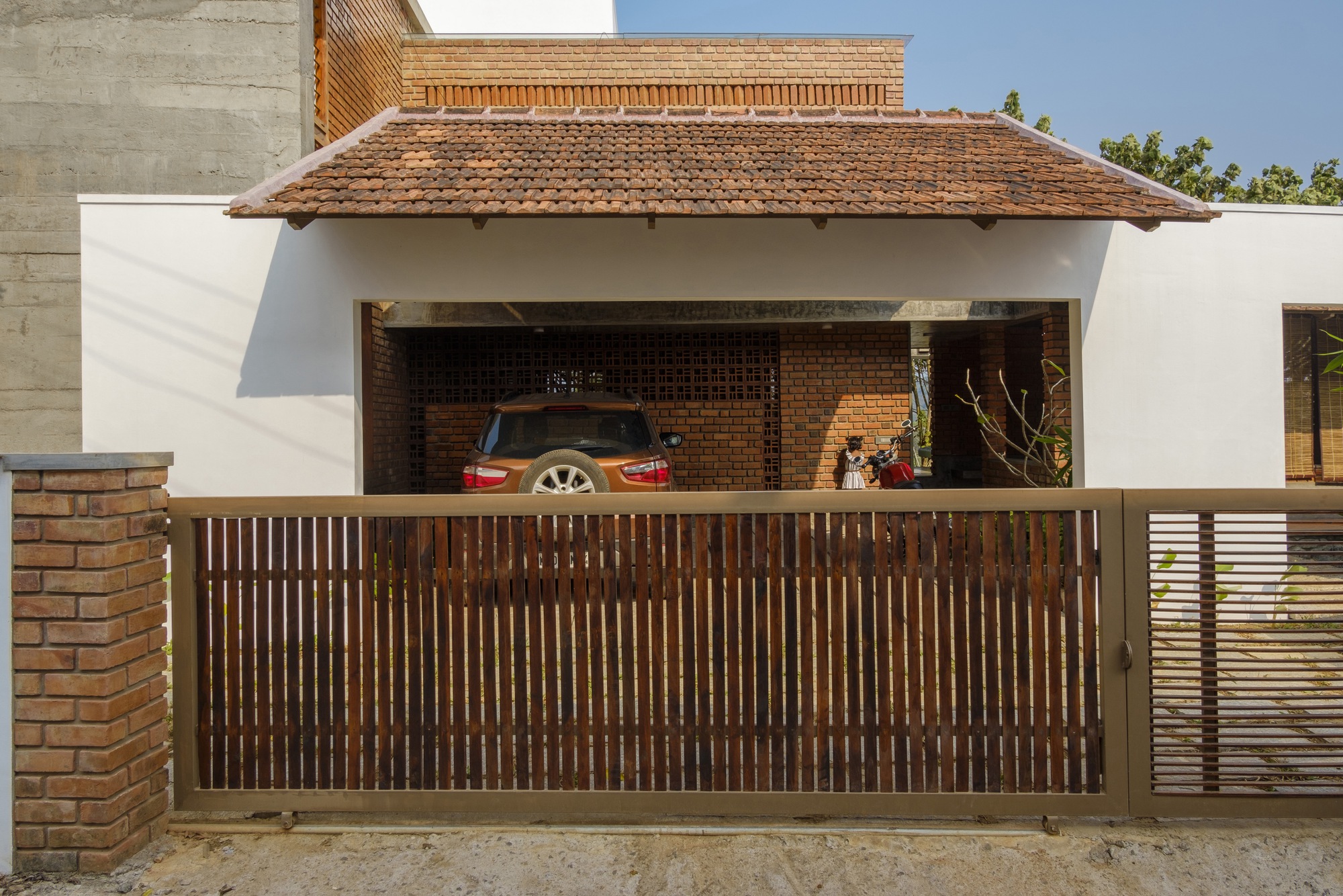 Timber slatted gate screening the open carport beneath a clay tile canopy