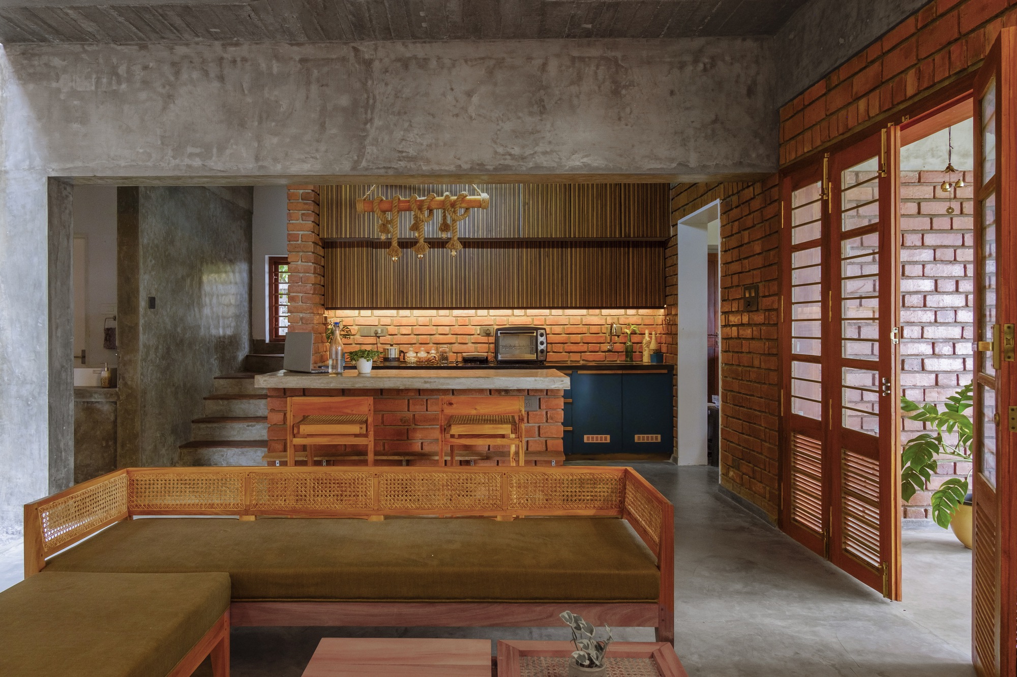 Open plan living area with exposed brick walls, concrete ceiling, and timber louvered doors
