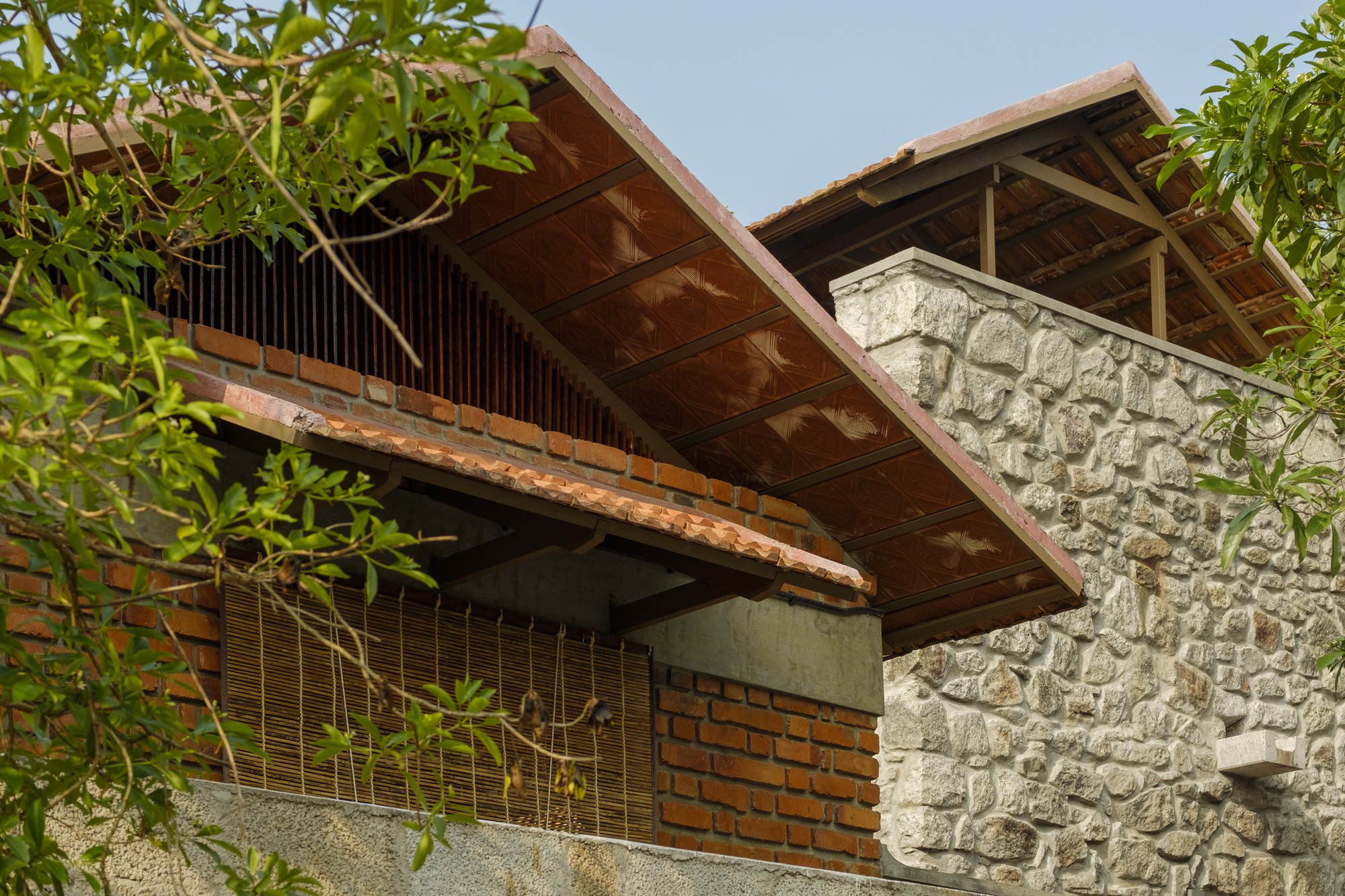 Upward view of timber-framed gabled roof with exposed rafters above painted stone and brick walls