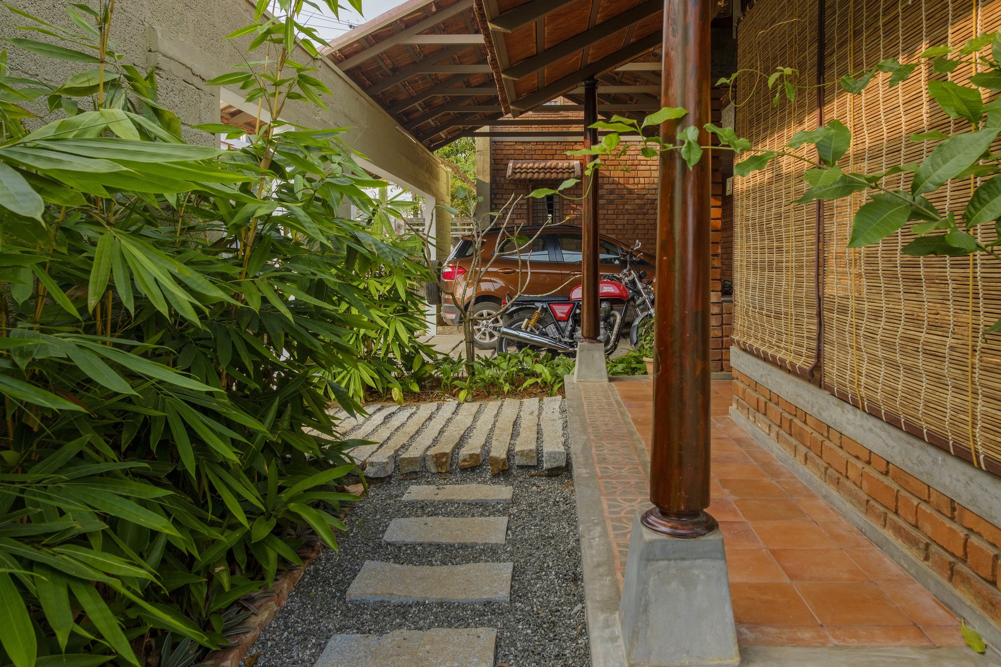 Covered walkway with timber columns and stepping stone path beside planted beds and bamboo screens