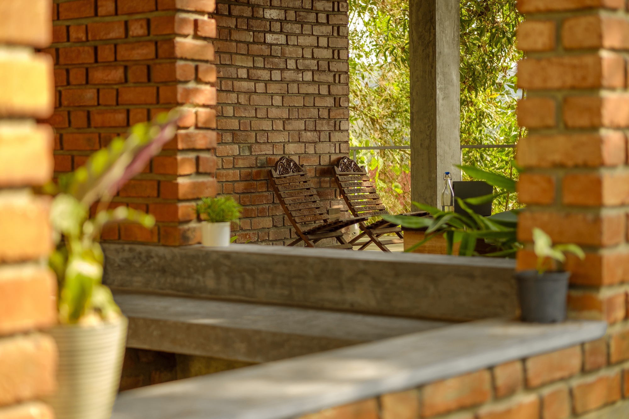 Split-level terrace with concrete steps, two folding chairs against brick wall, and bamboo screen framing the view