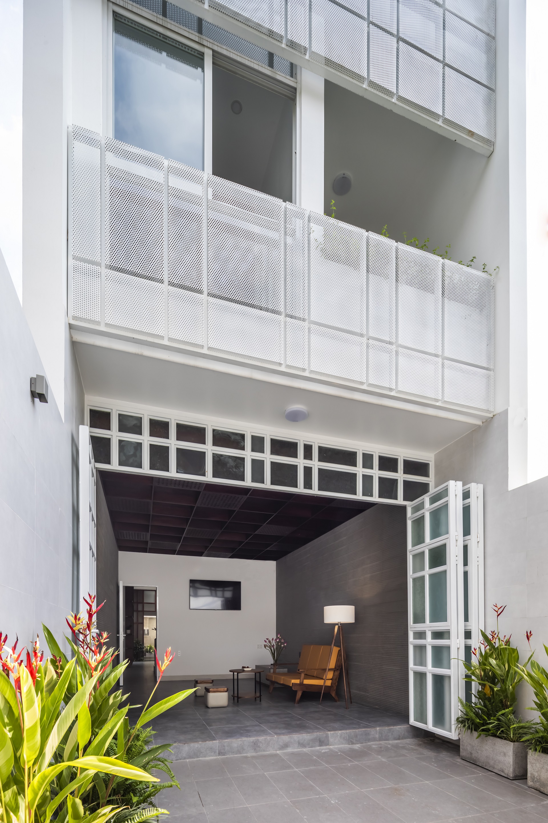 Open bi-fold glass doors leading into a sitting area flanked by potted tropical plants