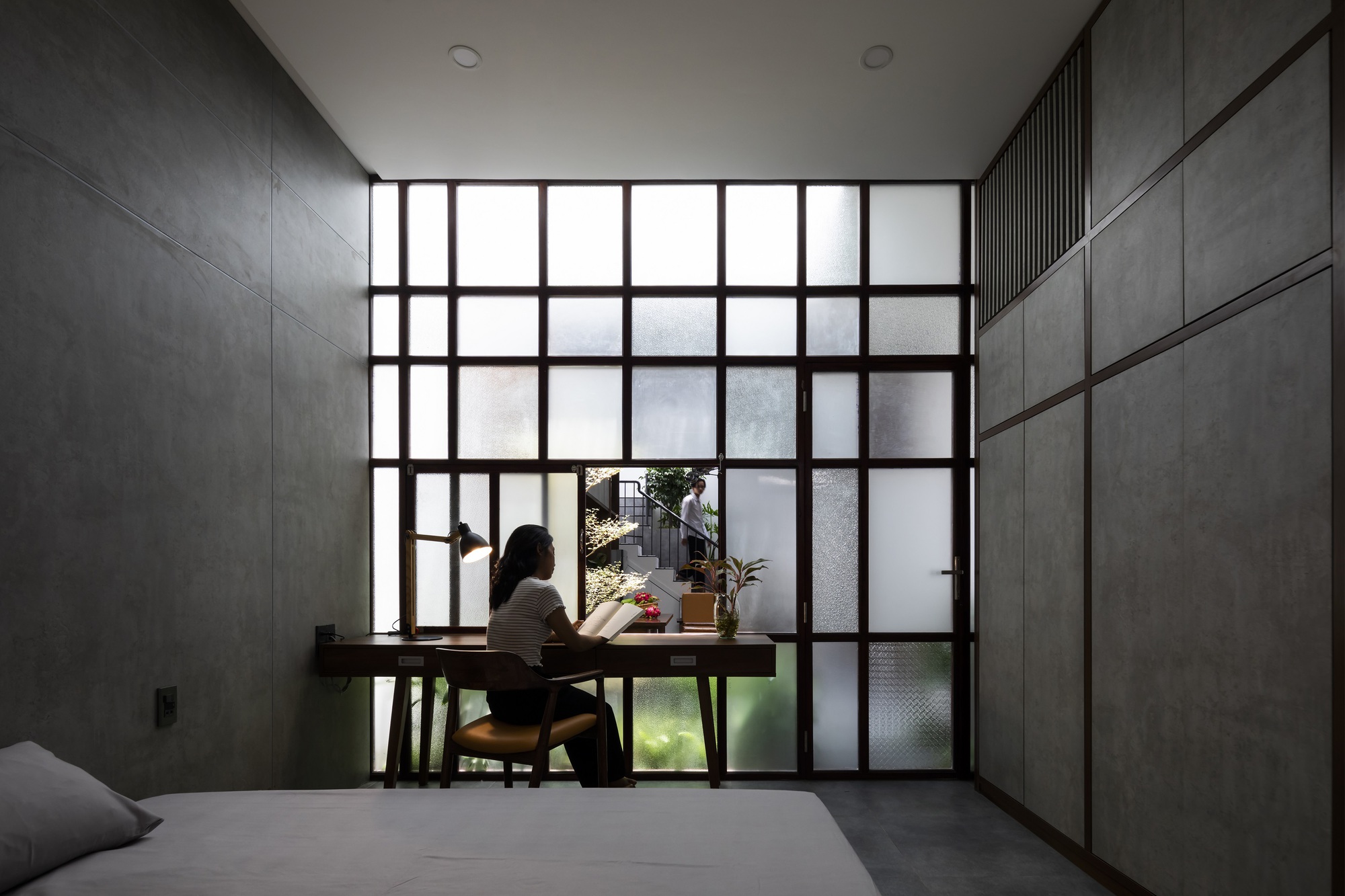 Person seated at a desk before a large gridded window overlooking an interior courtyard