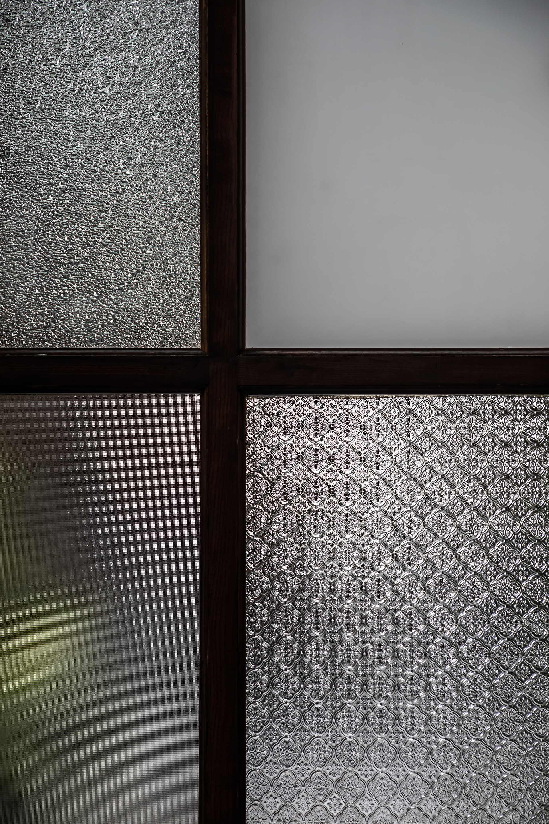 Four panes of textured and frosted glass in dark metal mullions filtering diffused daylight