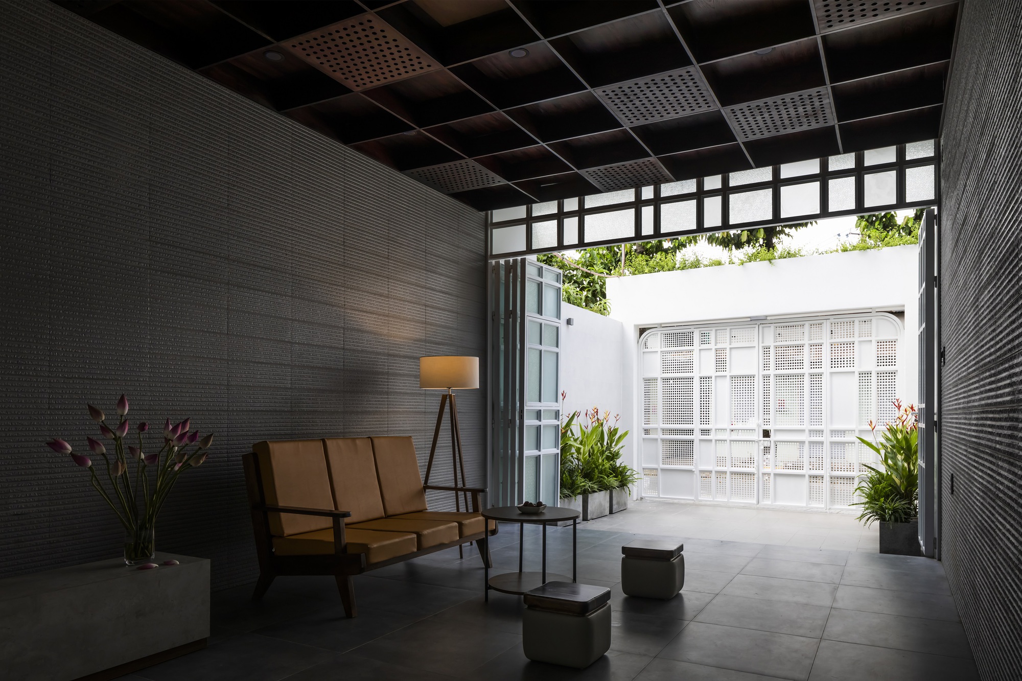 Interior lounge with dark textured walls and a view to the white courtyard facade through open doors