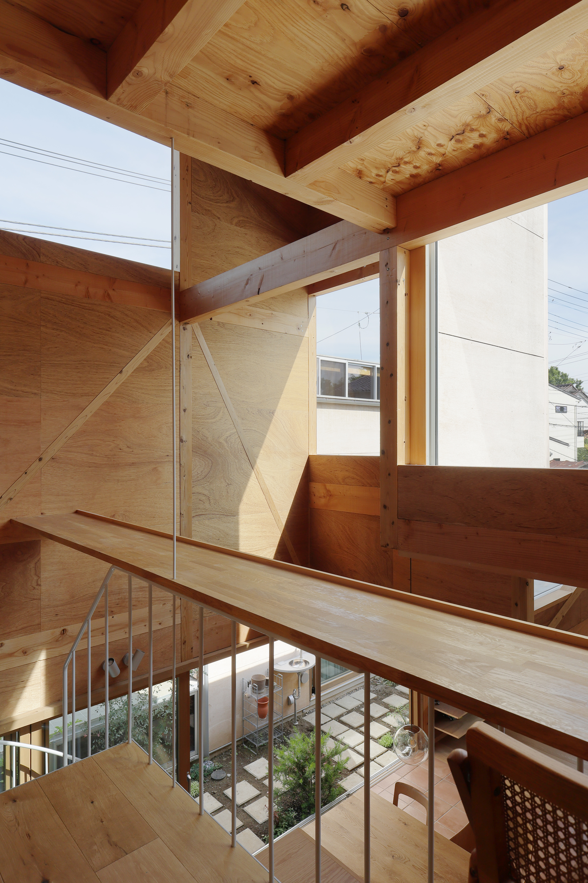 Mezzanine landing with plywood walls and exposed timber structure overlooking the planted courtyard below