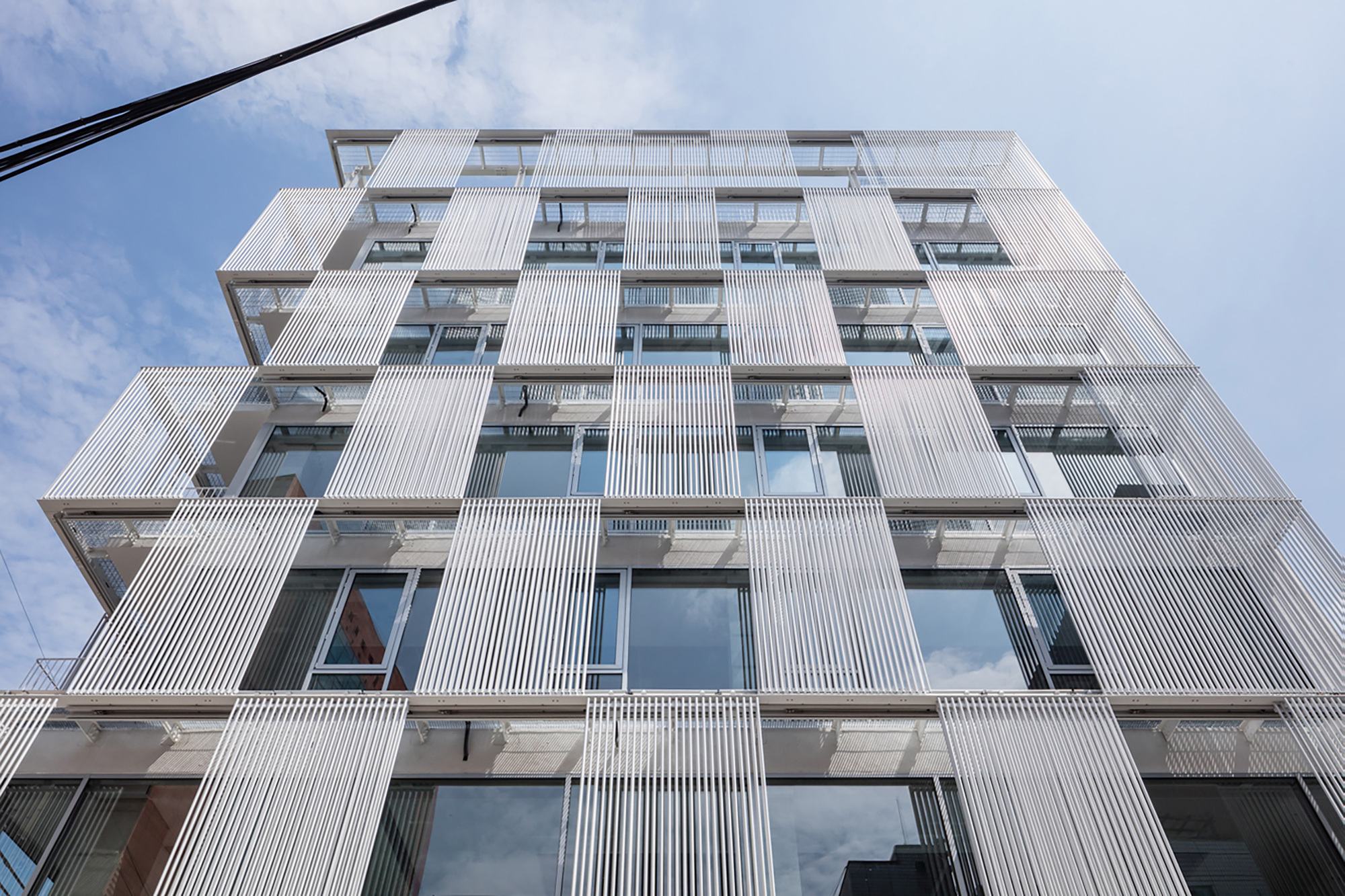 Looking up at the gridded facade showing vertical ribbed panels alternating with recessed window openings and balconies