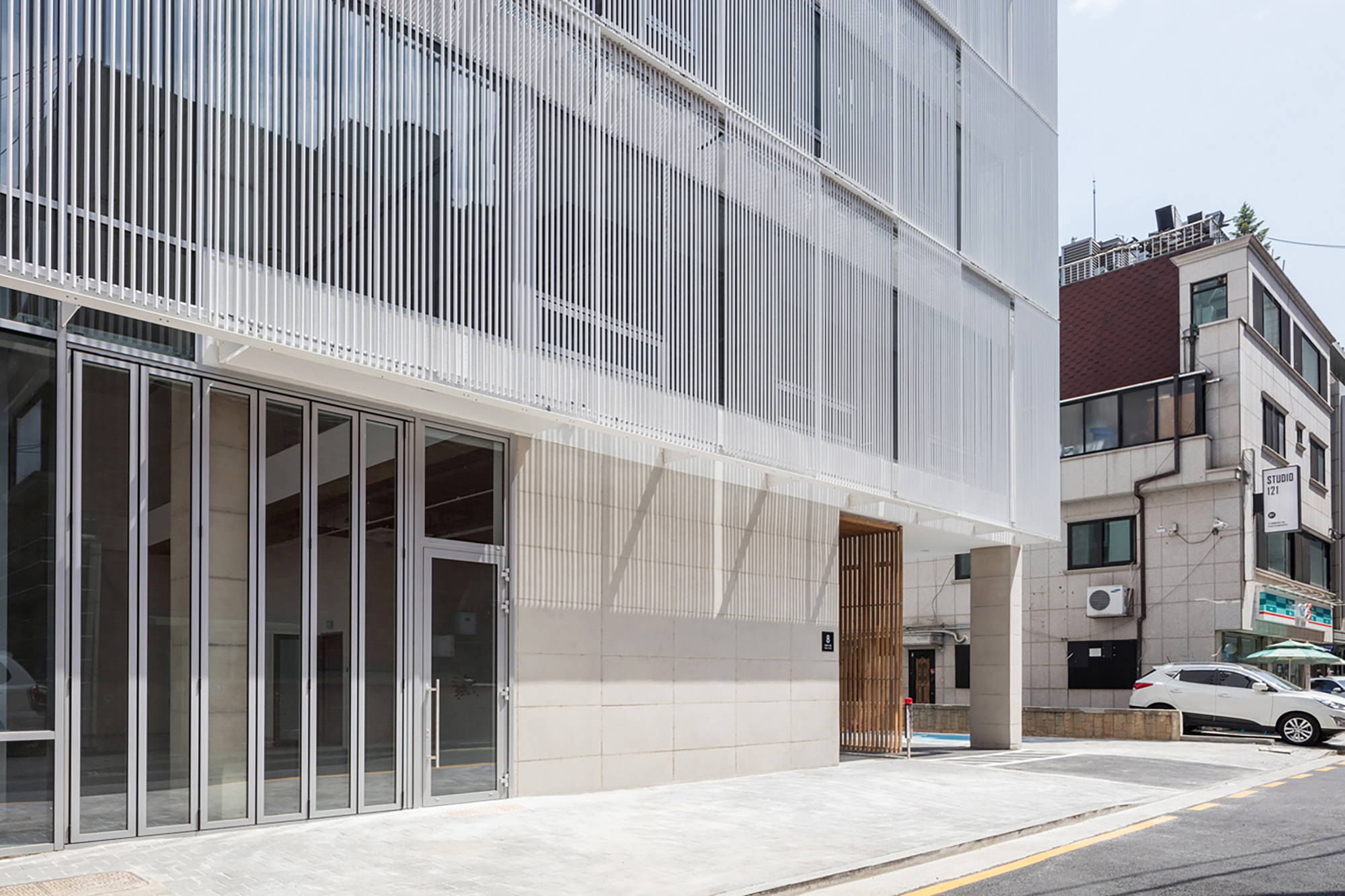 Ground level entrance with vertical fin screen above glazed storefront and timber door panel