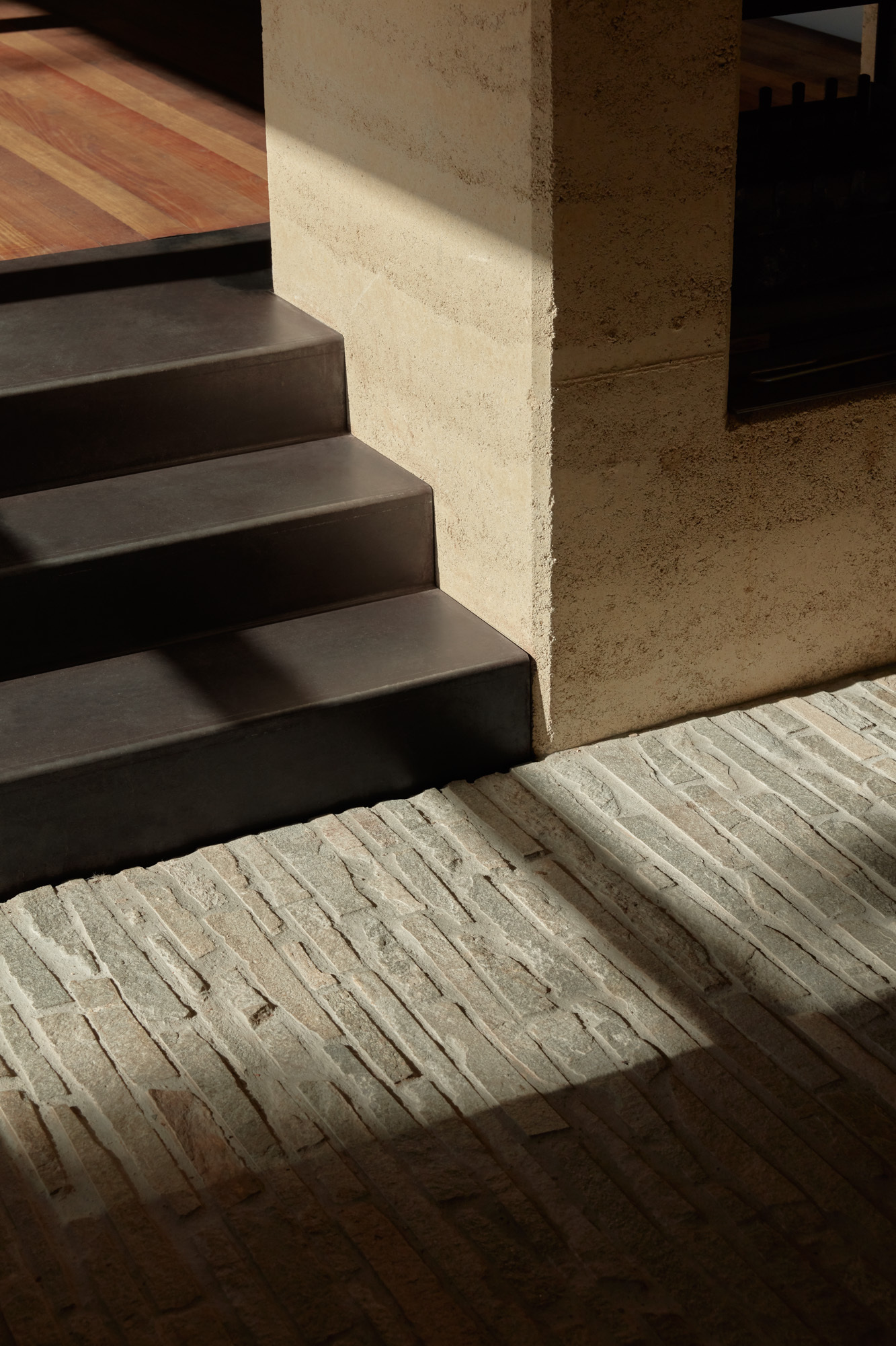 Steel stairs meeting ridged concrete paving where sunlight catches the textured surface