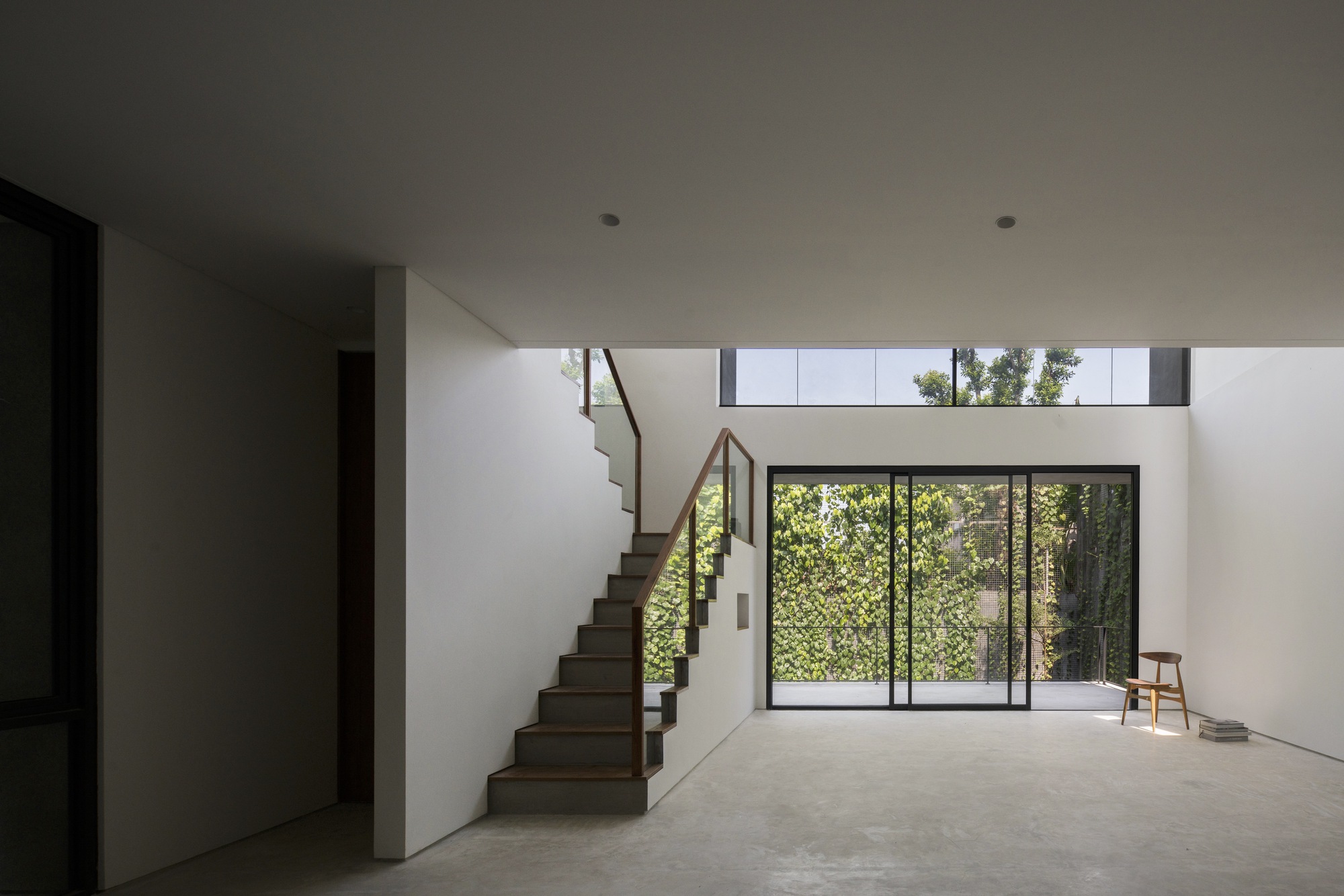 Open-plan living space with floating timber staircase and clerestory windows above courtyard glazing