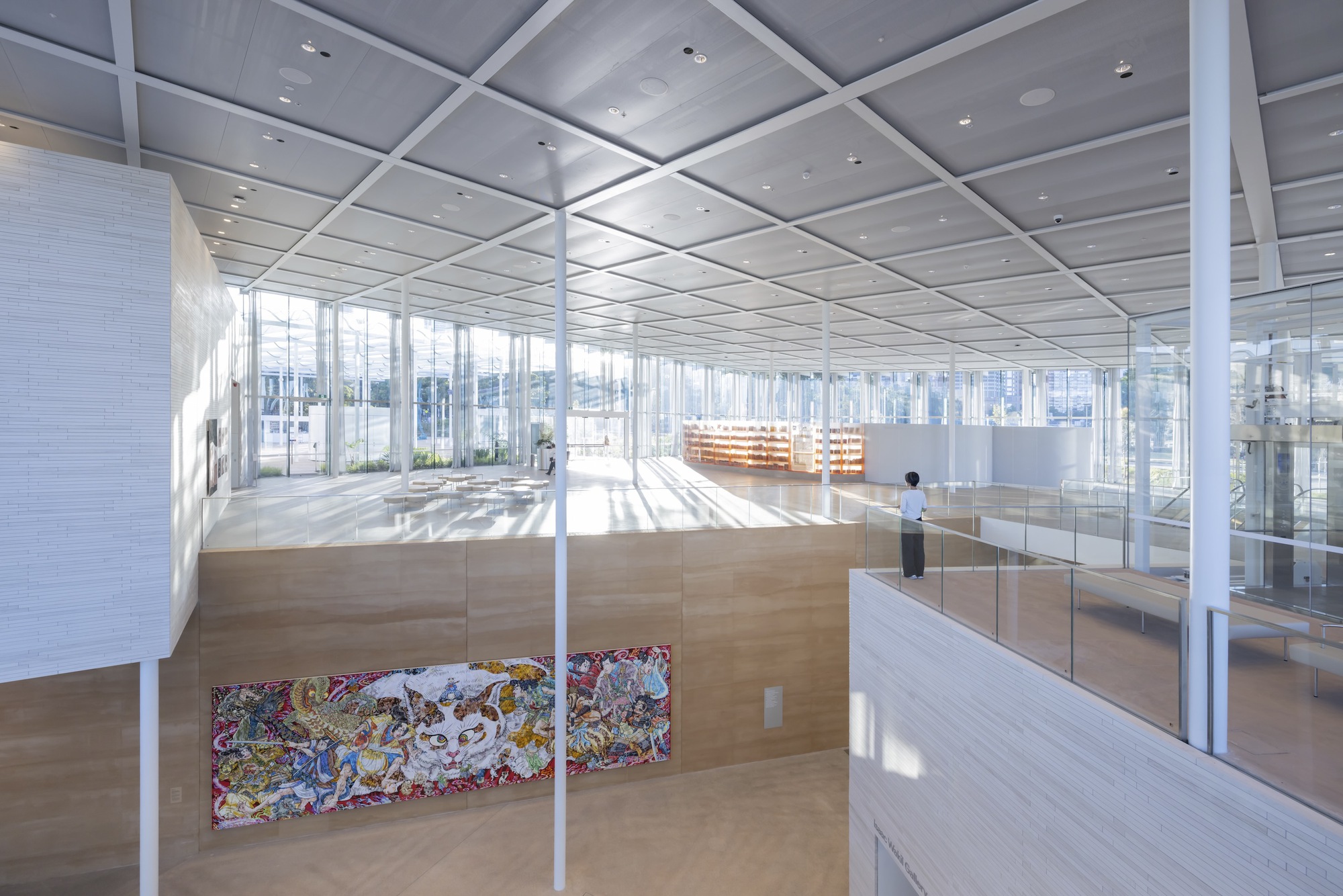 Interior gallery space with white structural grid ceiling and timber-clad walls in bright daylight