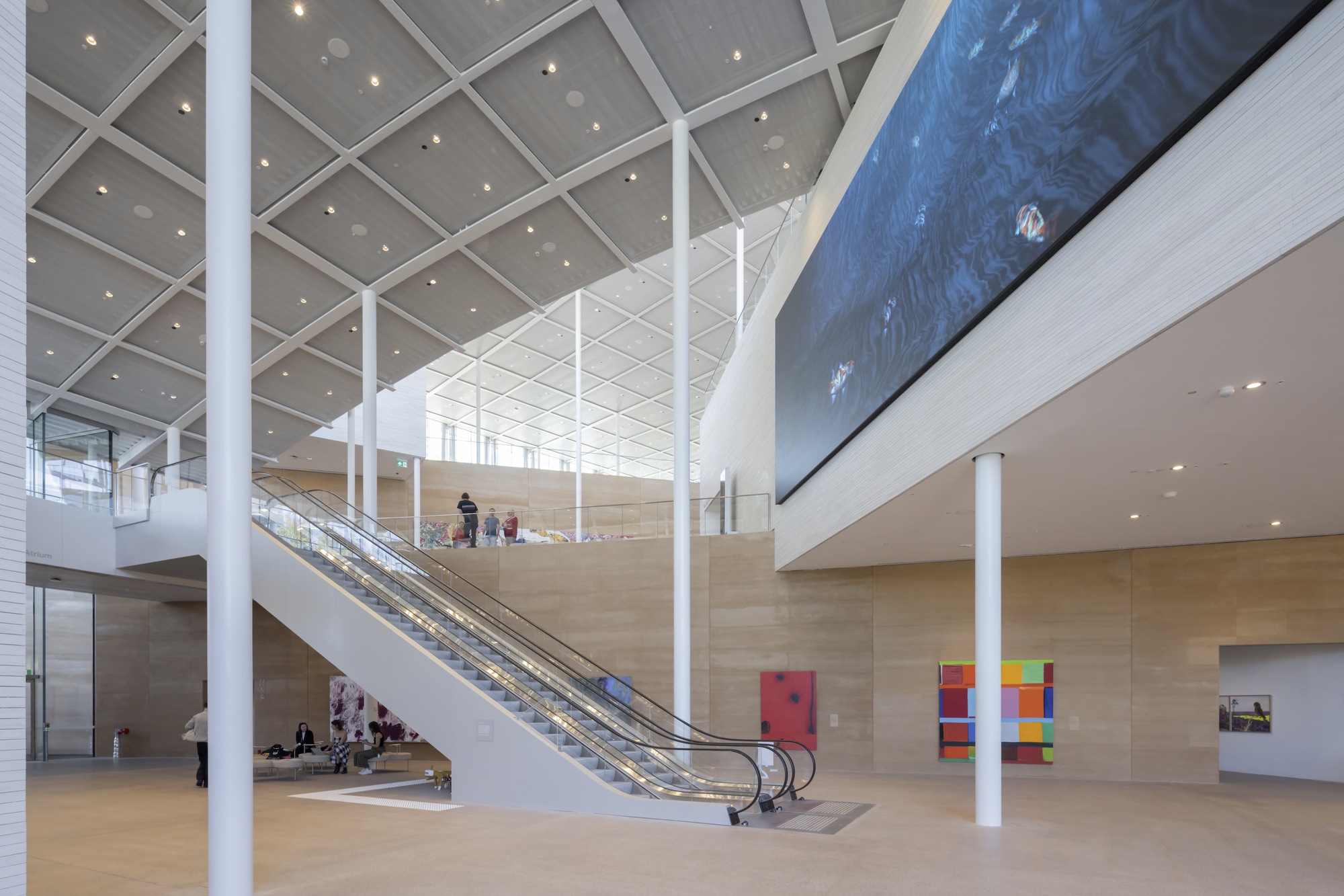 Multi-level atrium with escalators, white columns, and coffered ceiling under natural light