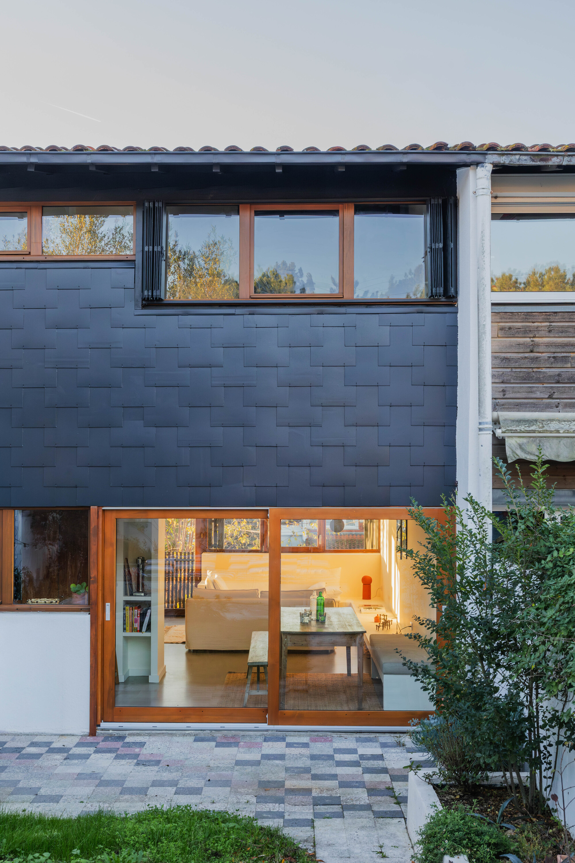 Rear elevation showing dark tile wall with sliding timber doors opening to a paved courtyard