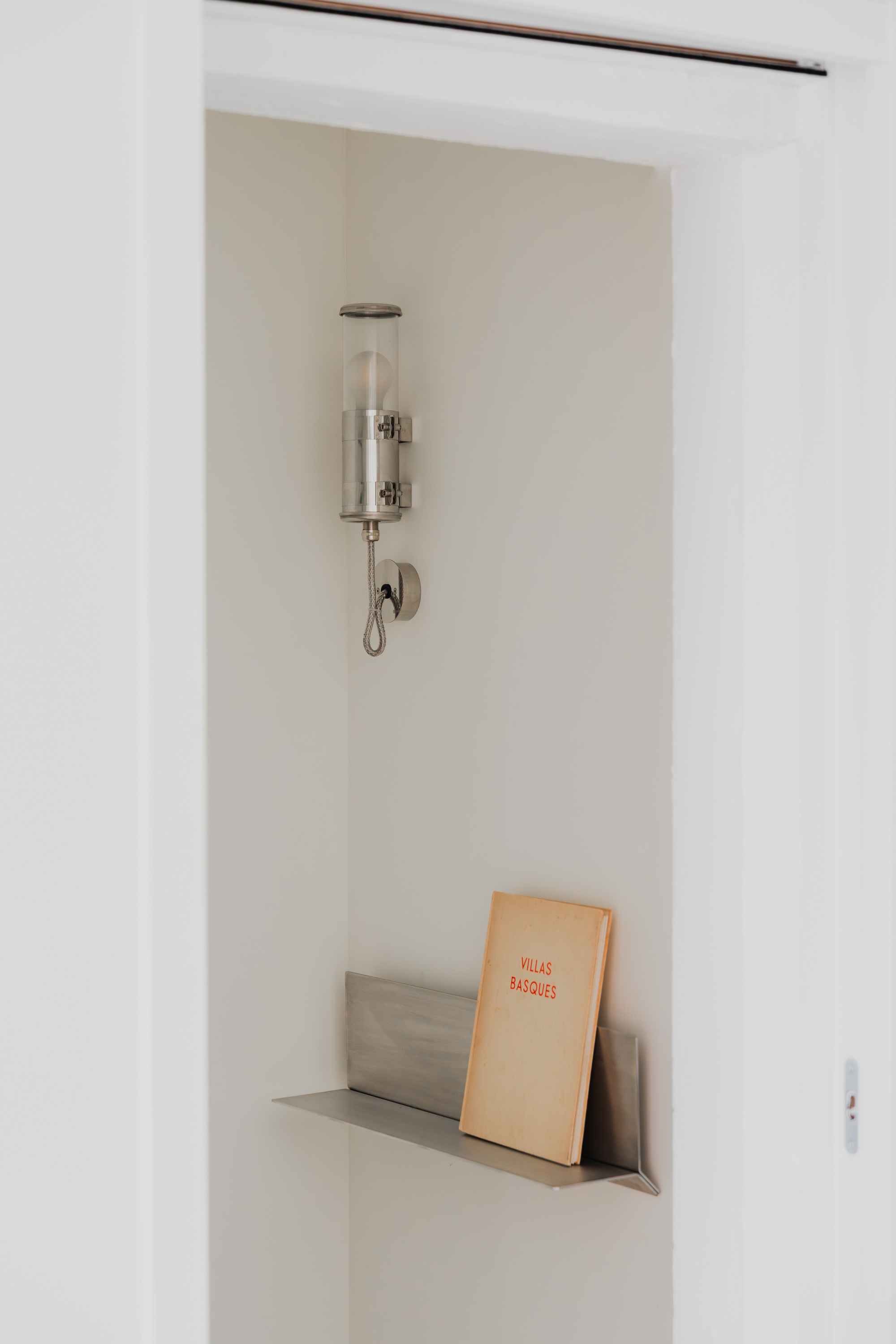 Built-in wall niche with glass sconce above and books on the ledge