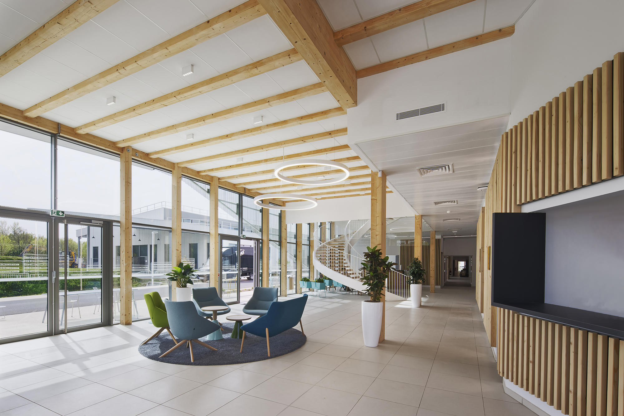 Lobby with exposed timber beams and vertical wood slat screens beside a seated cluster