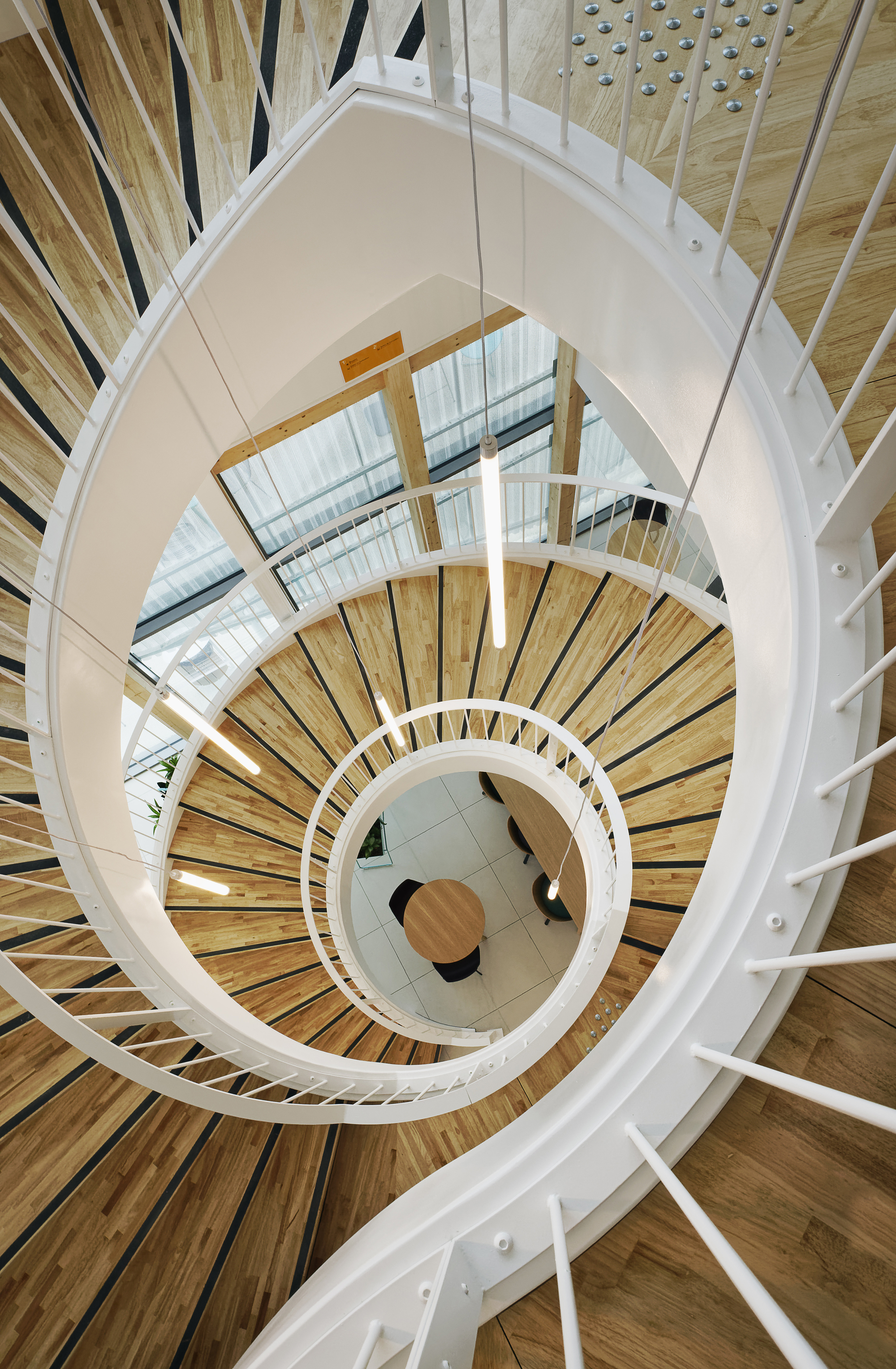 Looking down the helical stairwell with alternating wood and white curved steps around a central void