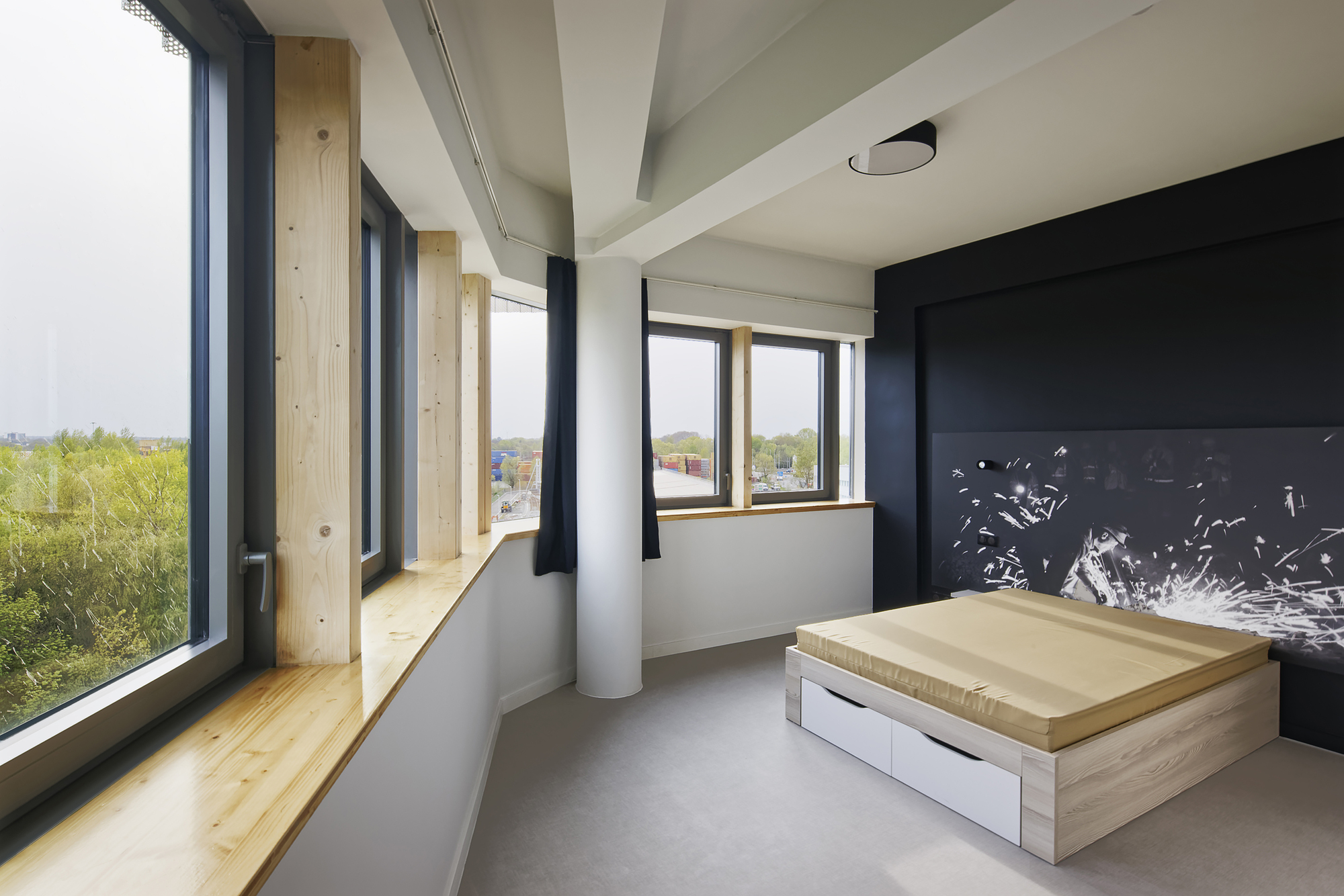 Corner room with exposed timber columns, polished concrete floor and a raised wooden platform bed