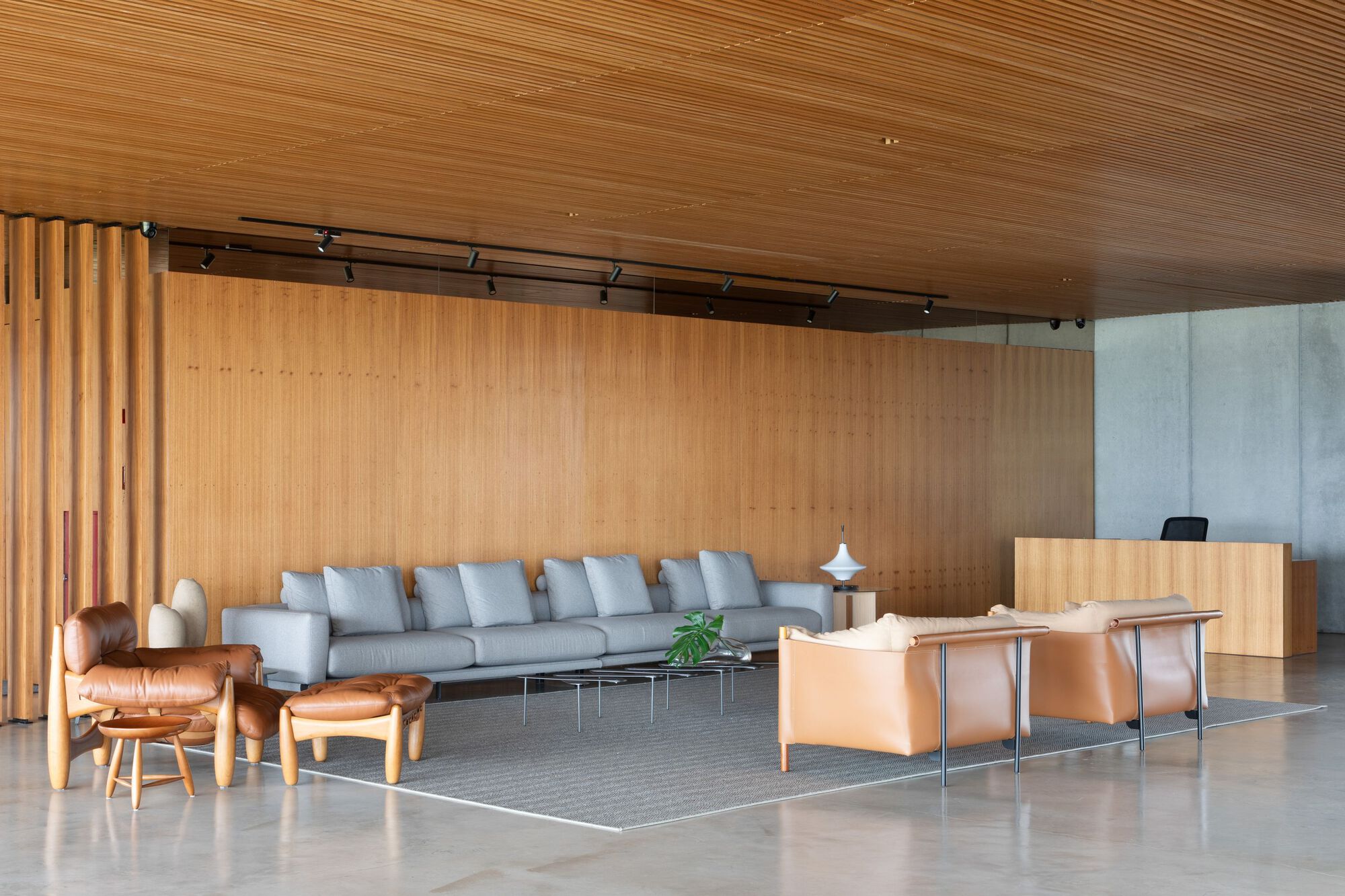 Open lobby space with slatted wood ceiling and concrete reception desk between seating zones