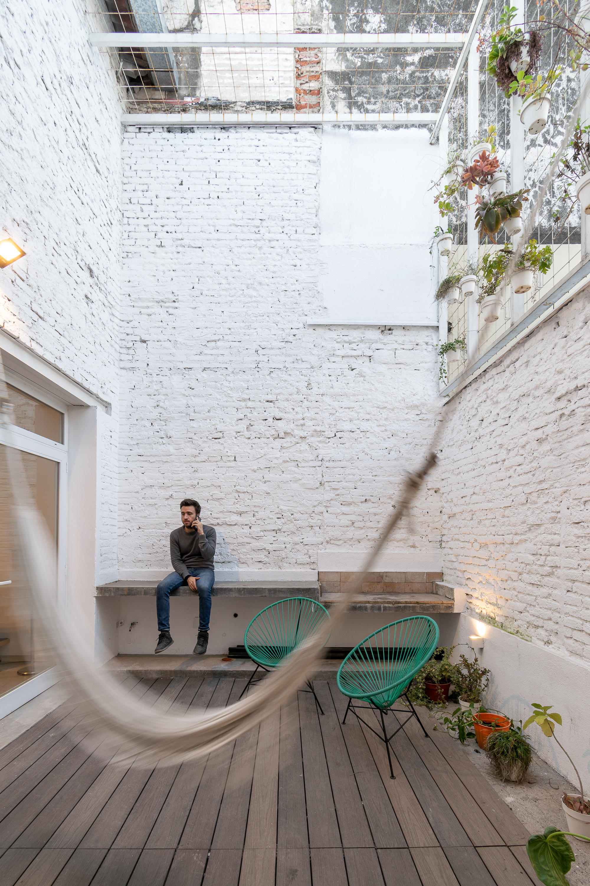 Courtyard with white-painted brick walls, timber deck, planted skylight and a seated figure
