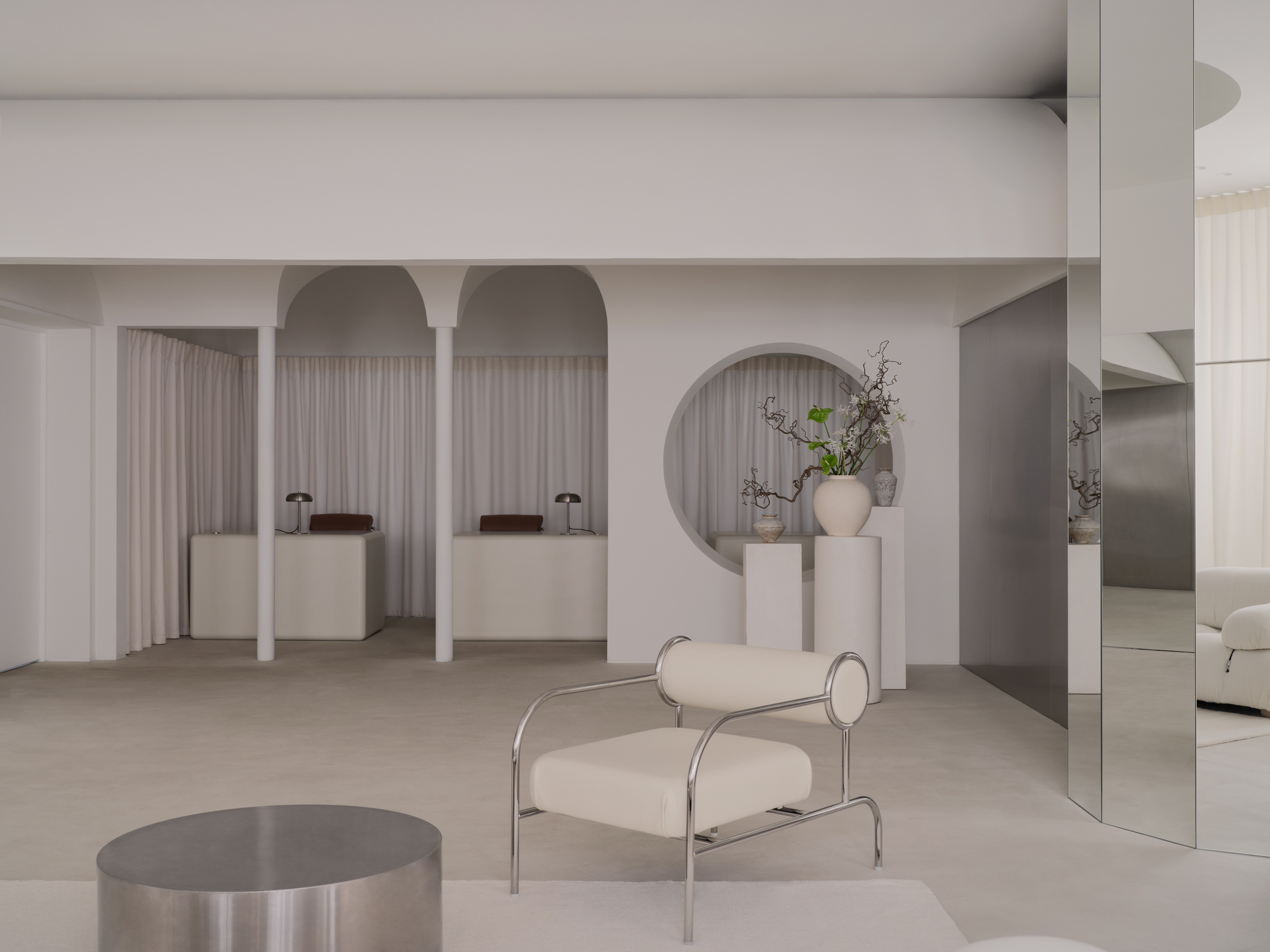 White arched niches with draped curtains and display plinths beneath a pale vaulted ceiling