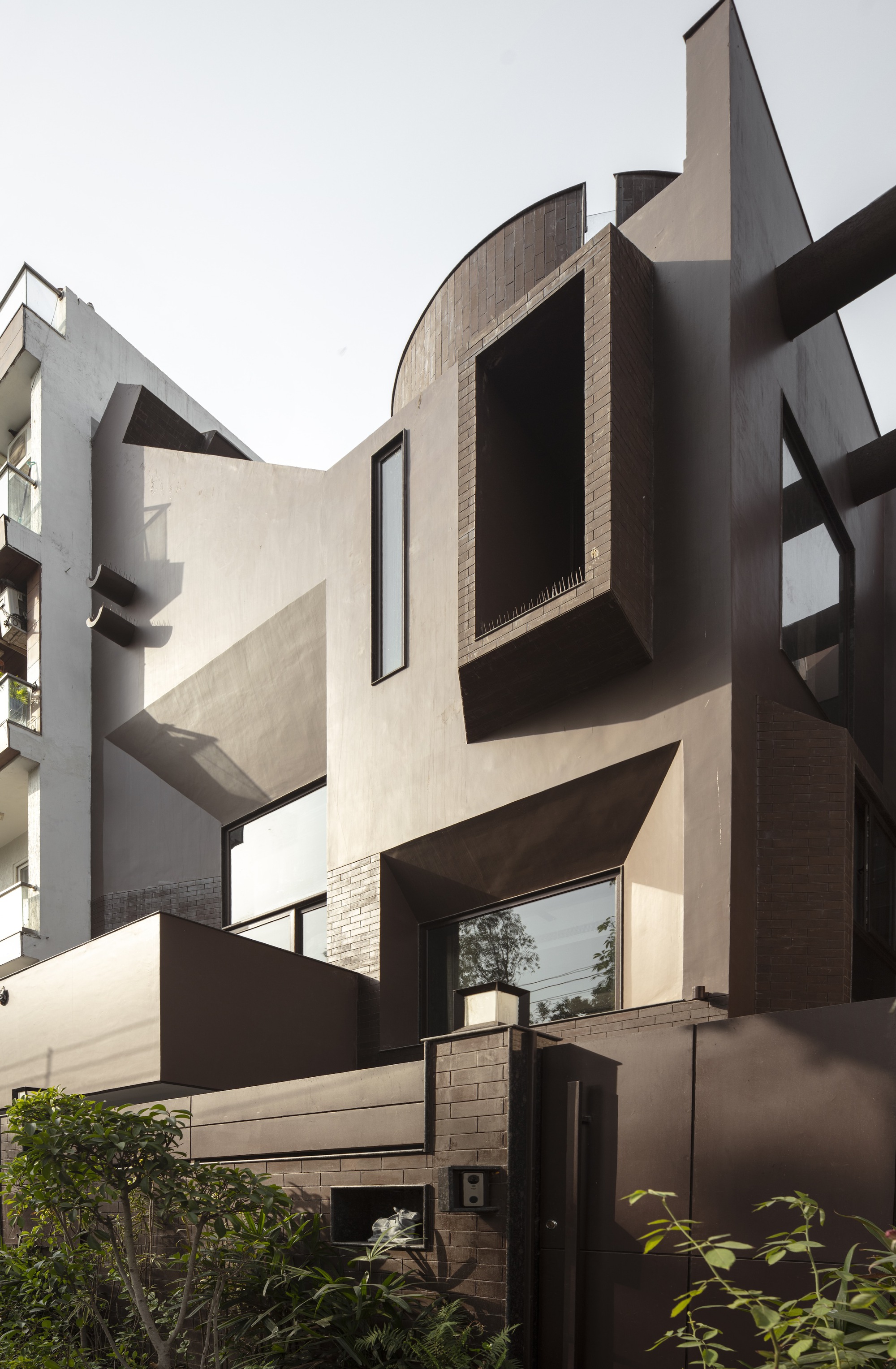 Courtyard view showing angular facade volumes with brown panels and protruding window boxes in daylight