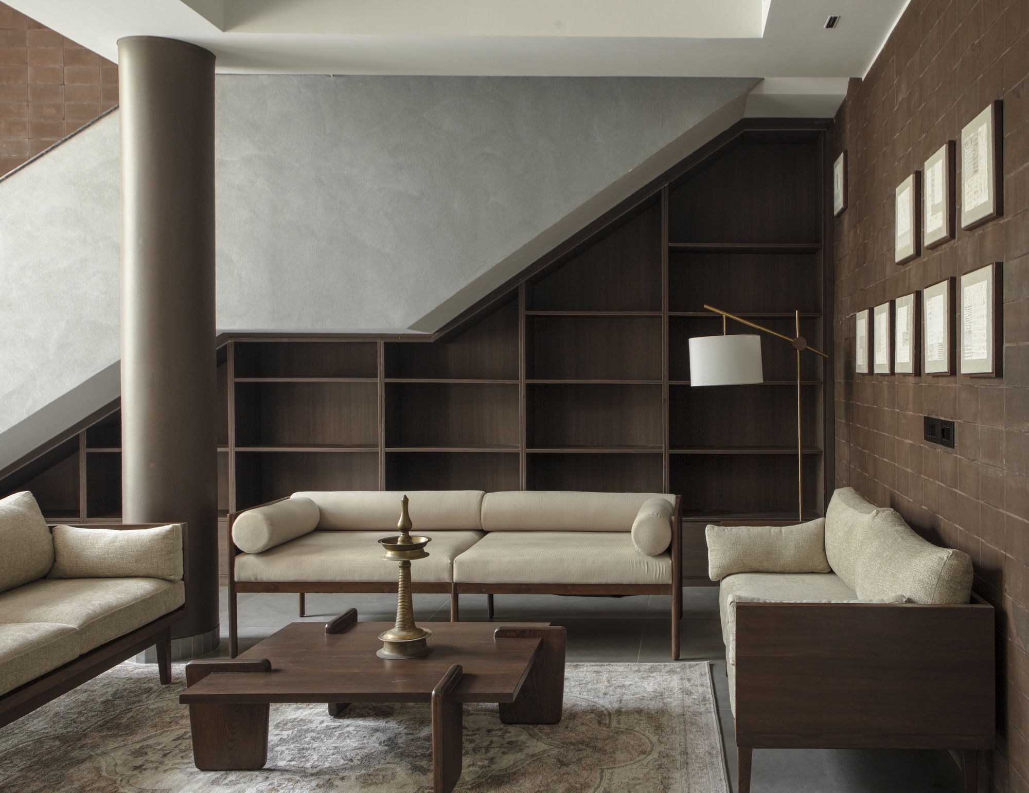 Double-height living room with dark wood shelving beneath an angled skylight and cylindrical column