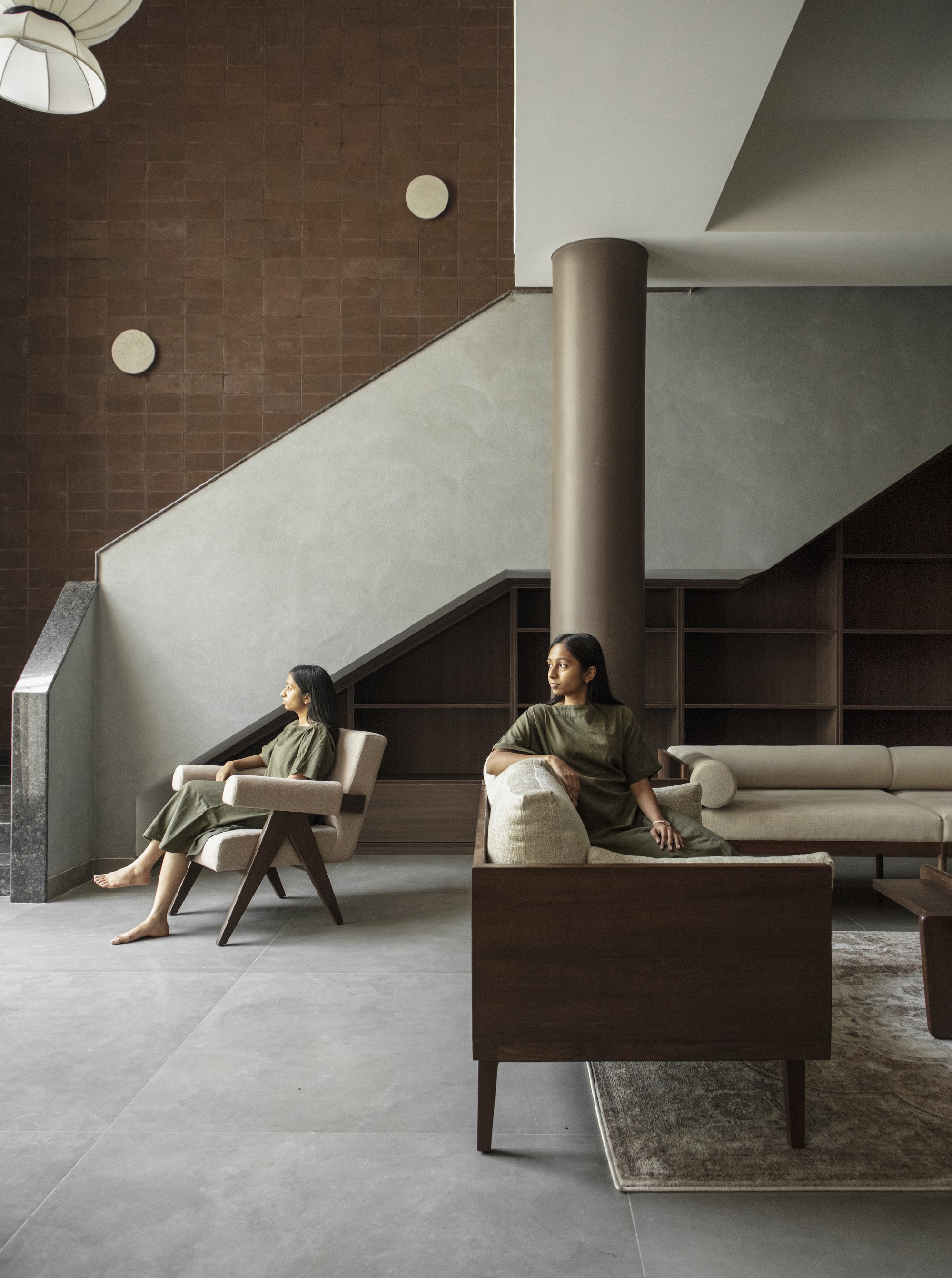 Interior view showing staircase with plaster balustrade and two figures seated in the lounge below