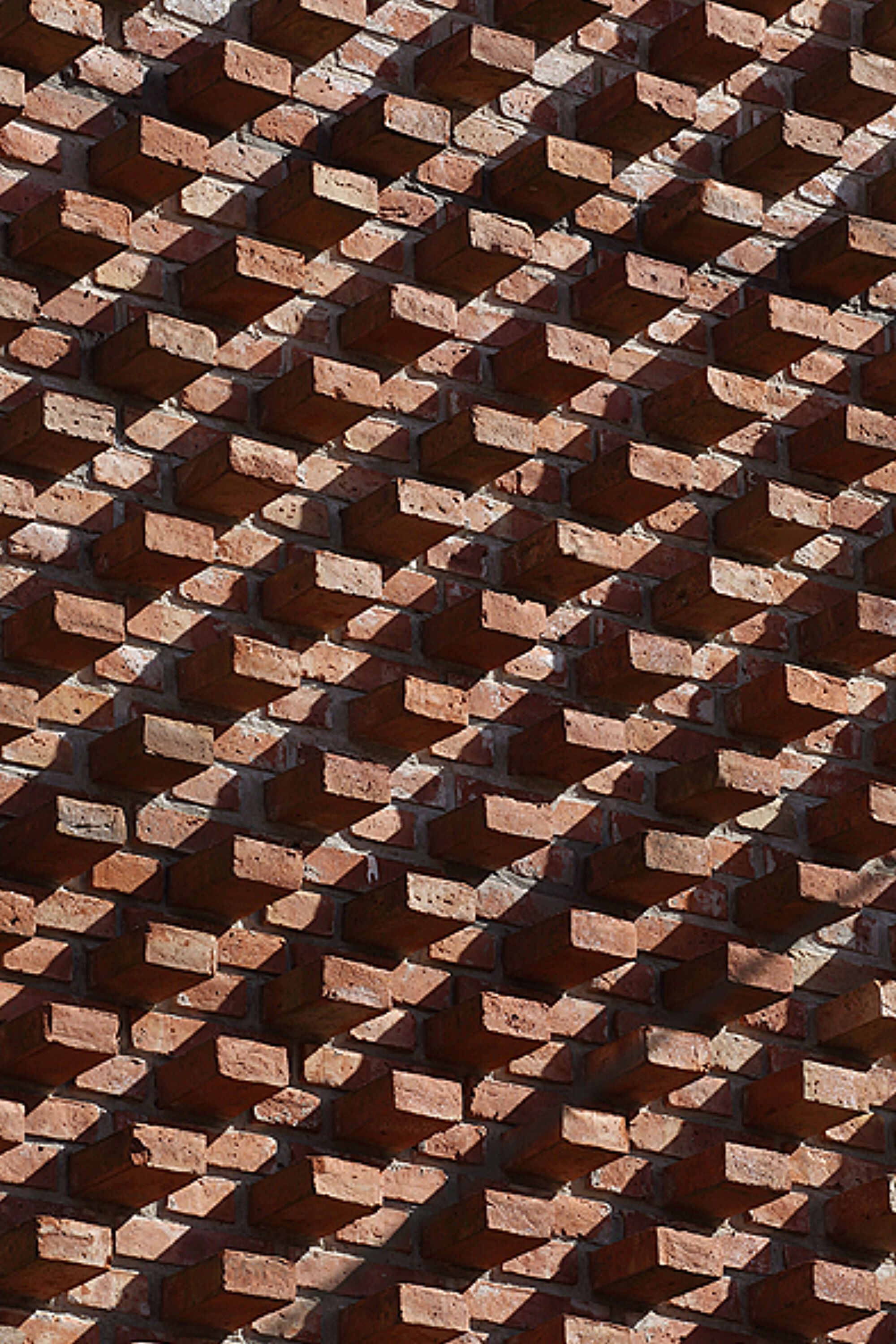 Detail of diagonal brick pattern with deep shadows cast by projecting units
