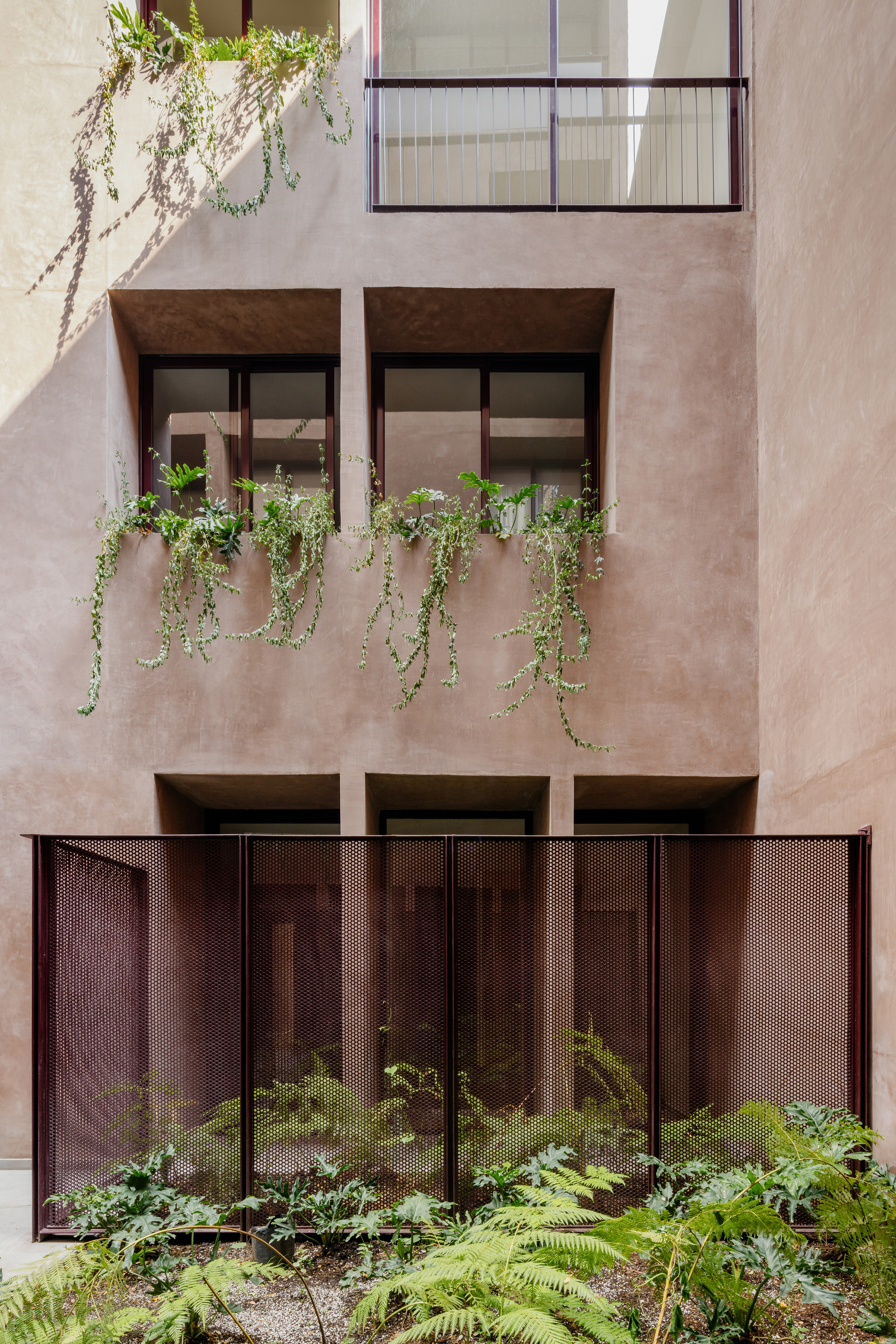 Interior facade showing planted window boxes with trailing greenery and perforated metal panels below