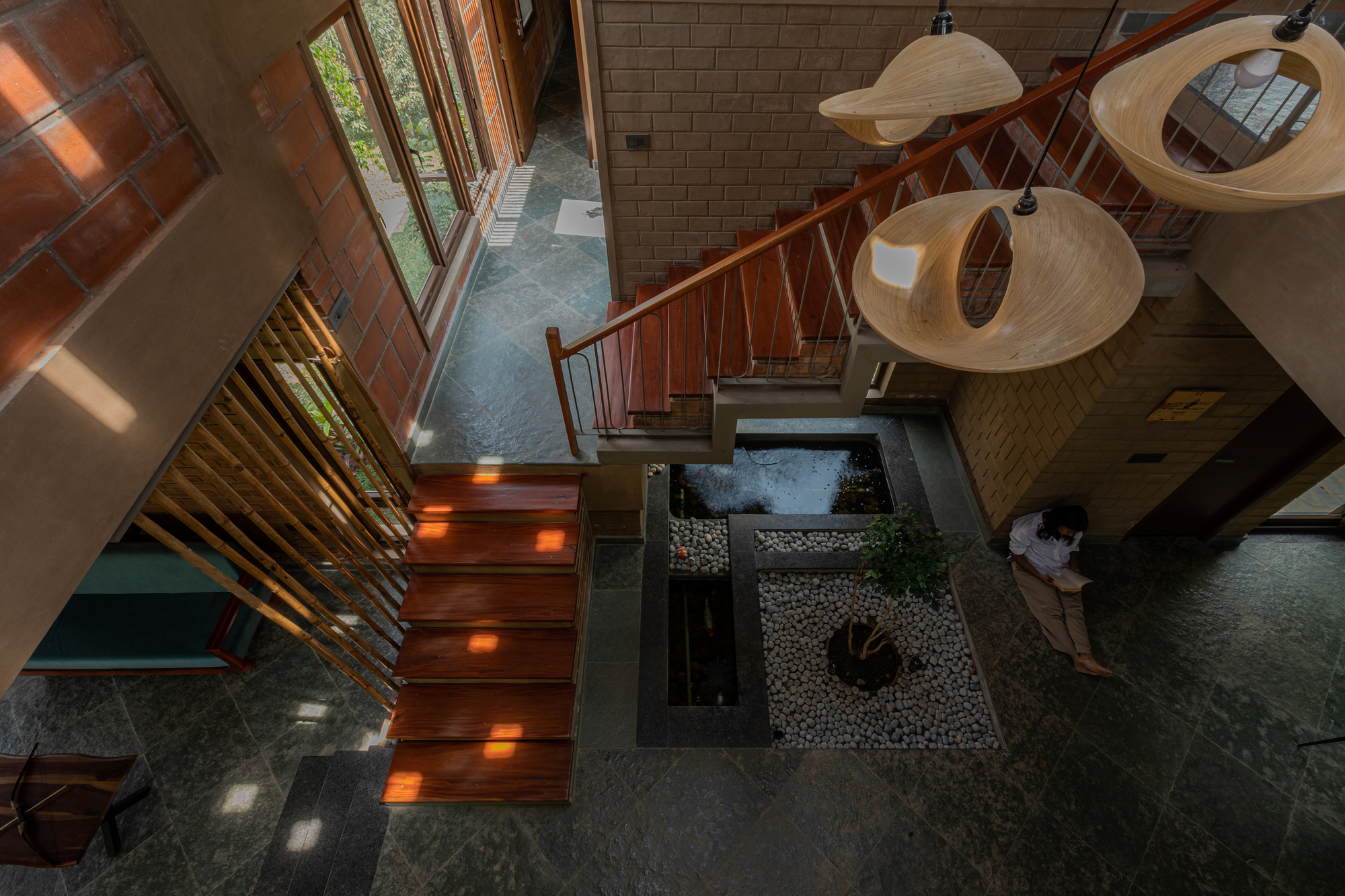 Overhead view of the timber staircase with integrated lighting descending past the interior courtyard with water feature