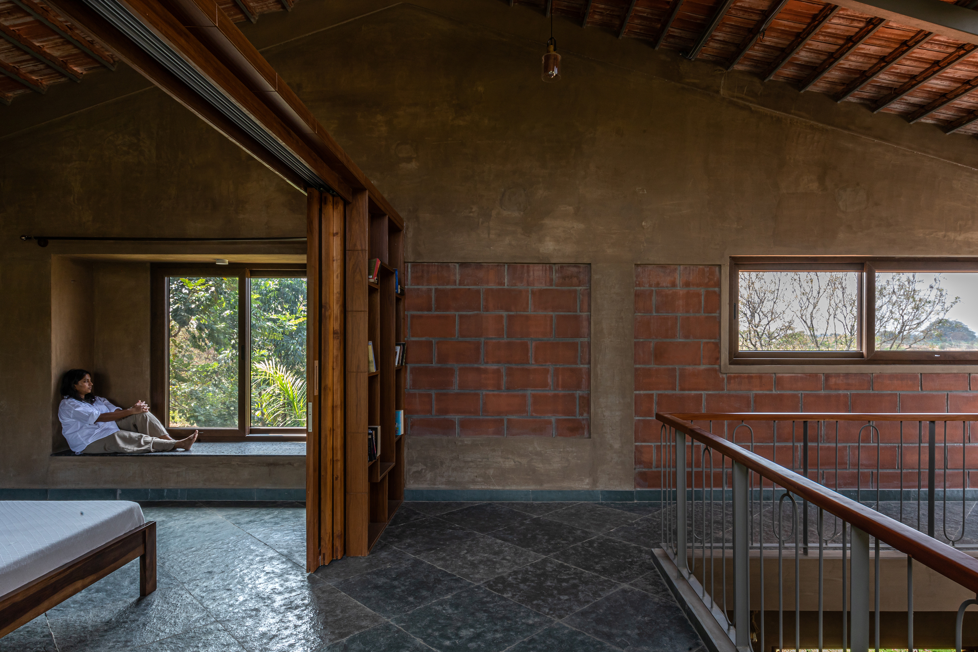 Bedroom with recessed window seat overlooking greenery and steel railing at the stair opening
