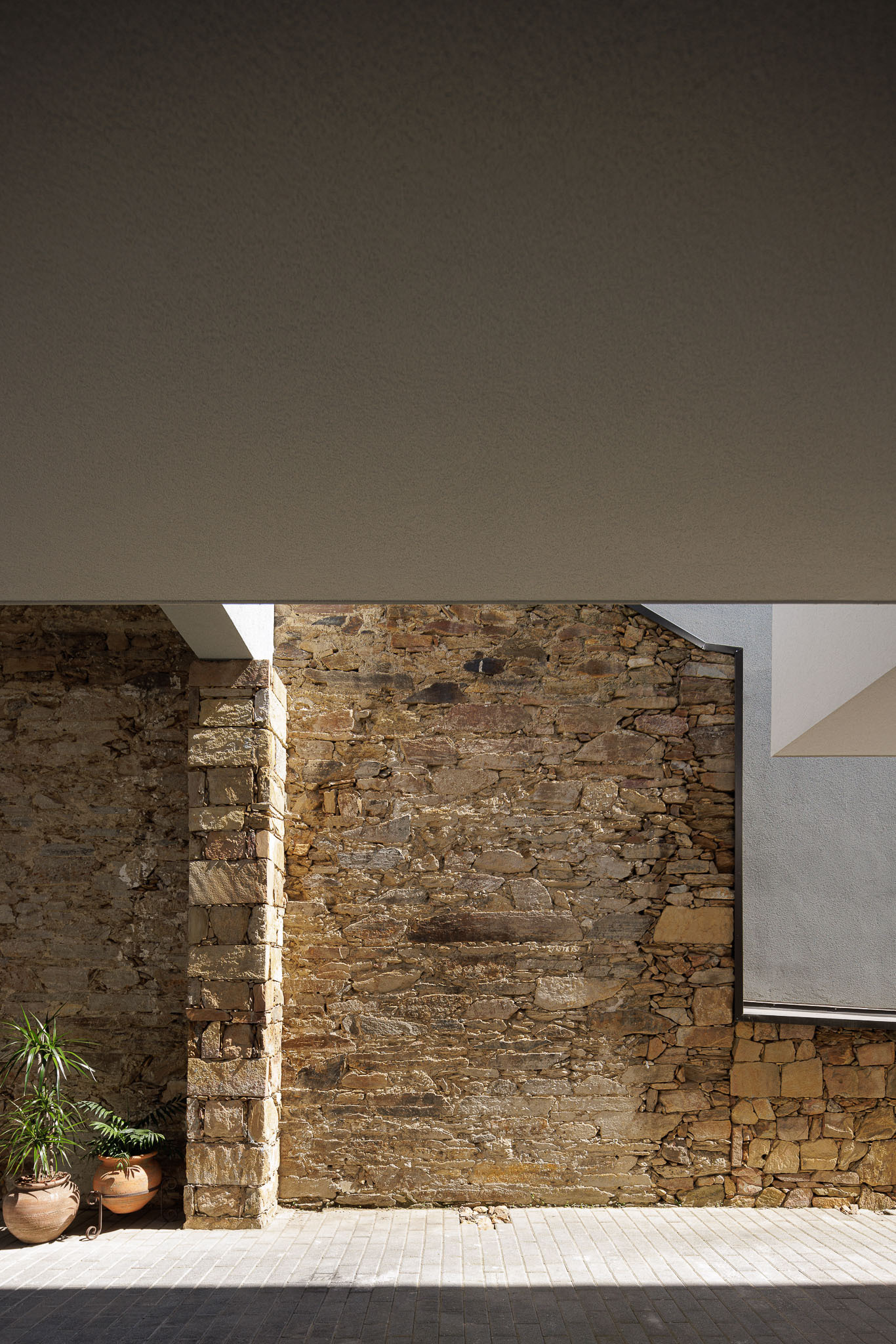 Narrow vertical slot of daylight illuminating a ruined stone wall beneath a canopy