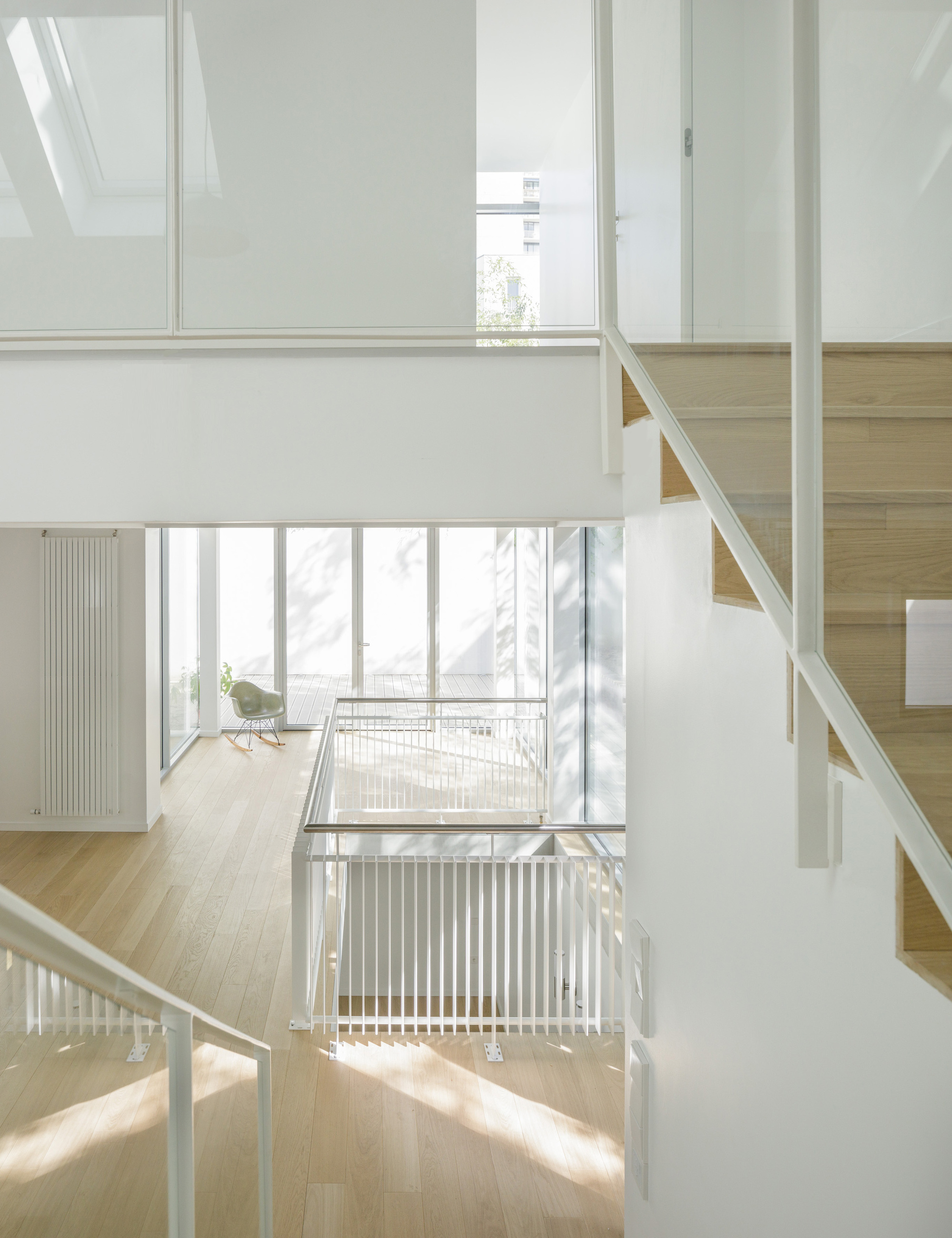 Multi-level interior atrium with light wood floors and vertical metal railings bathed in natural daylight