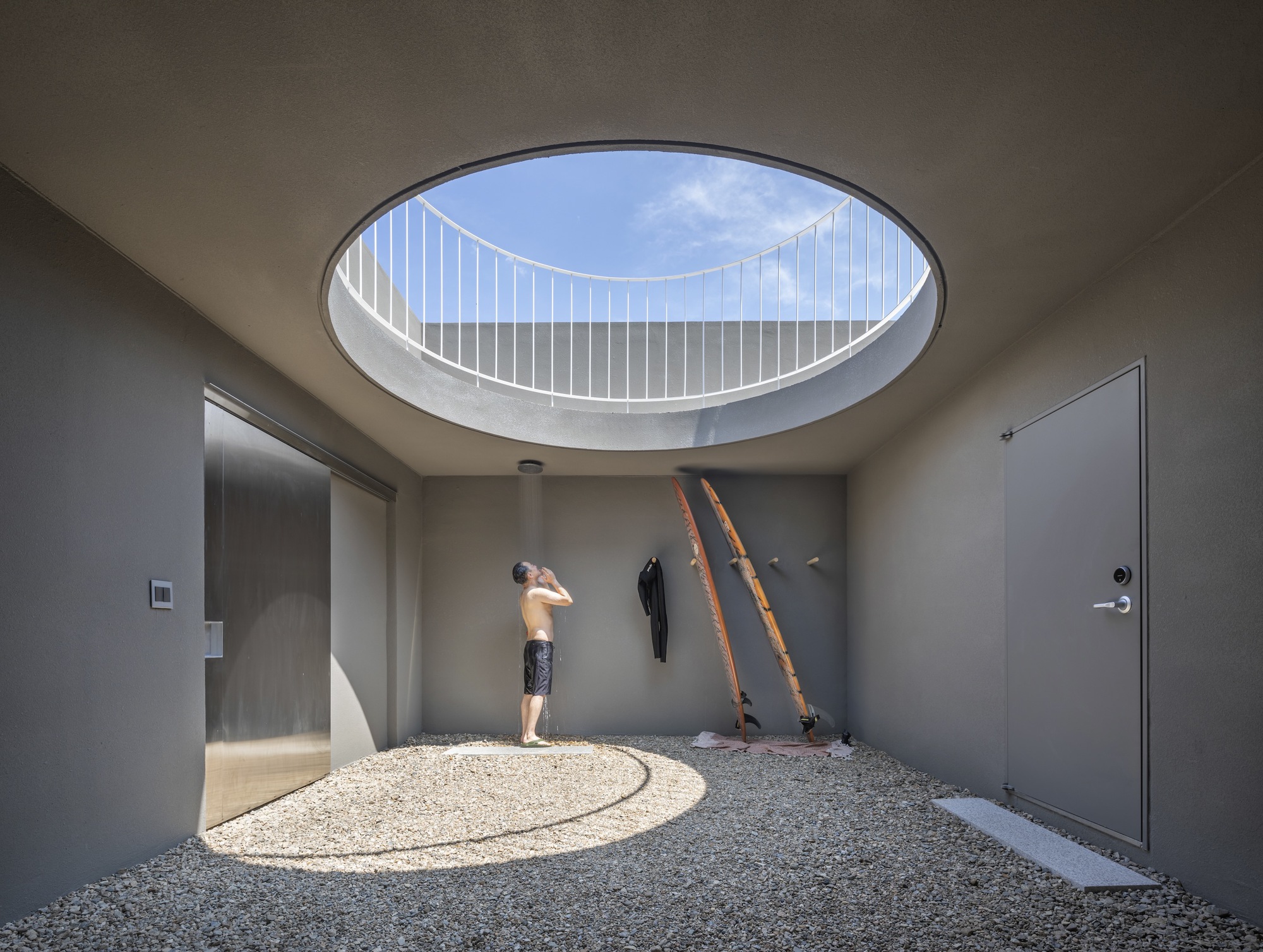 Entry hall with circular skylight above a gravel floor where a child stands in afternoon sun